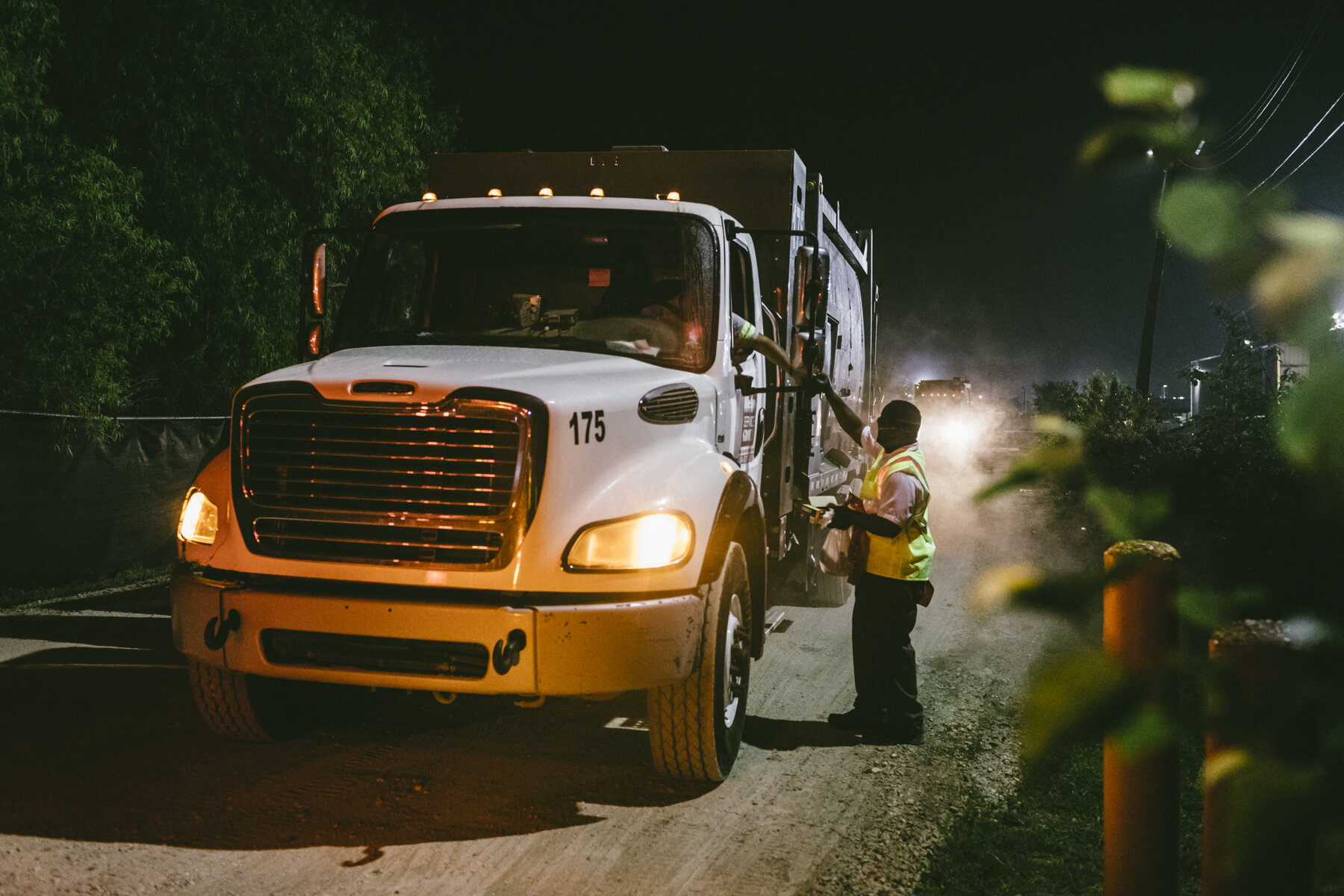  New Orleans, LA - March 24, 2020 - Isaac Brooks (51) hands a stack of clean cotton handkerchiefs up to a truck driver in the pre-dawn hours at Metro Service Group, one of three companies that manage residential trash collection in the city of New Or