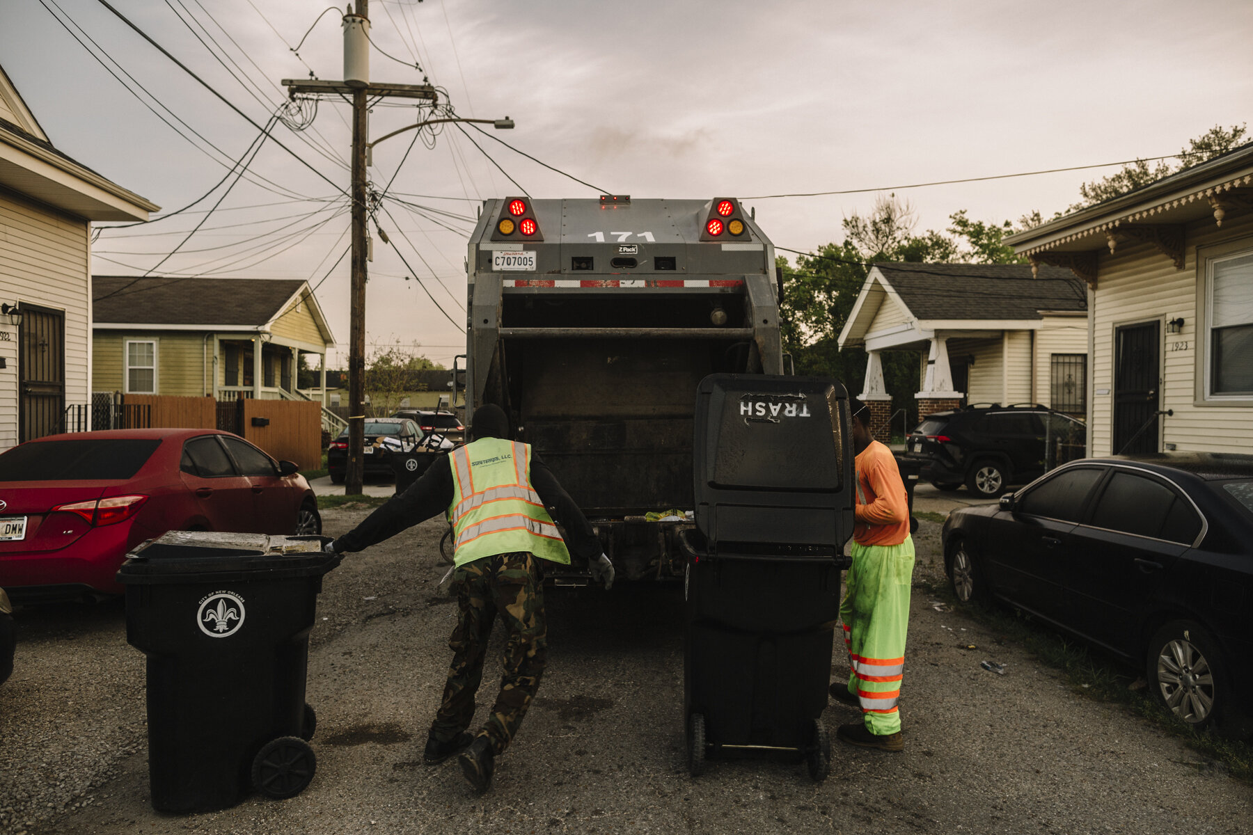  New Orleans, LA - March 24, 2020 - Garbage collectors empty residential garbage cans into the back of a Metro Service Group truck in the 7th Ward of New Orleans.  The company has begun furnishing extra rubber gloves, facemasks, and handkerchiefs to 