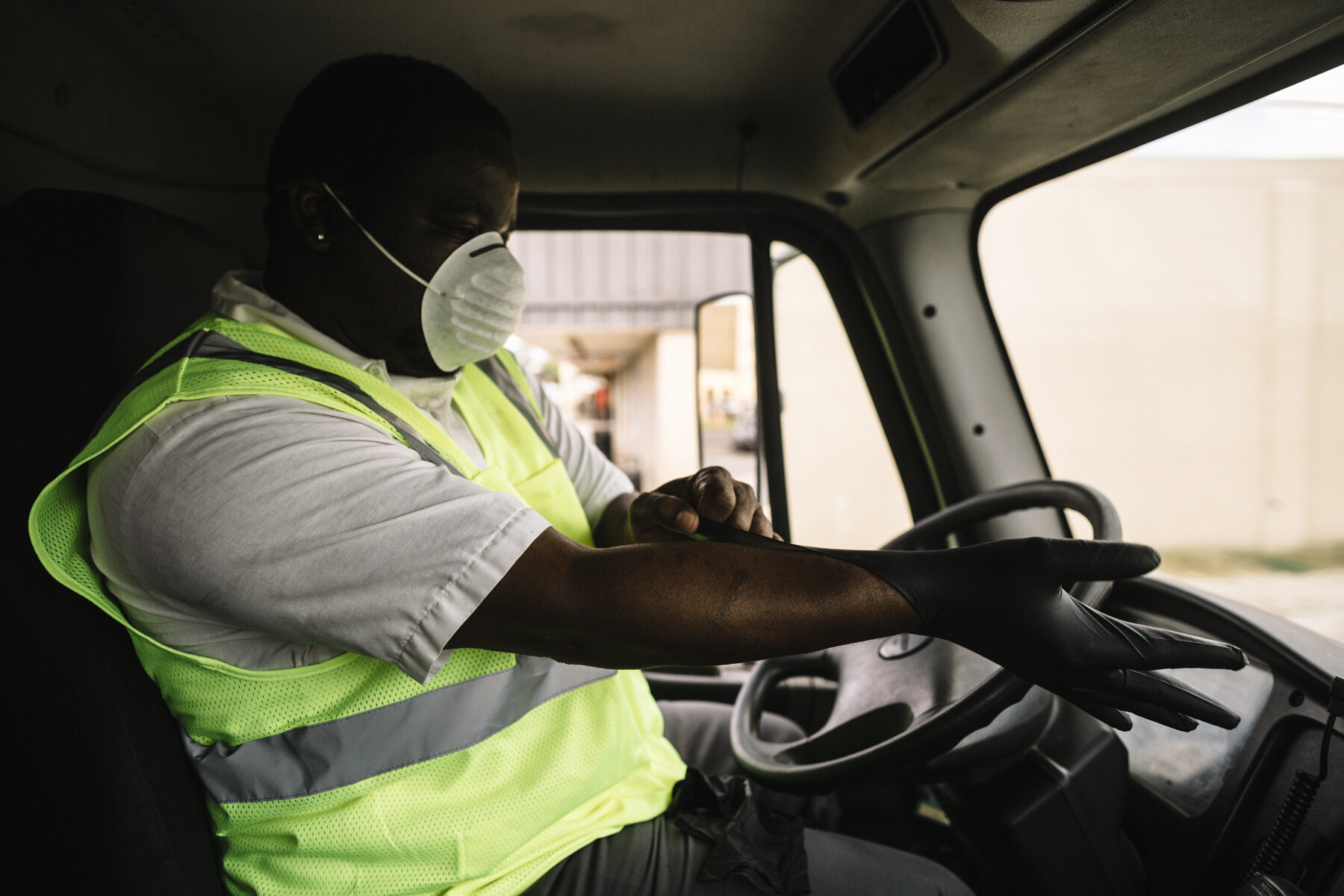  New Orleans, LA - March 24, 2020 - Isaac Brooks (51) pulls on a new pair of rubber gloves after spraying his steering wheel down with disinfectant. Brooks is a supervisor at Metro Service Group, one of three companies that manage residential trash c