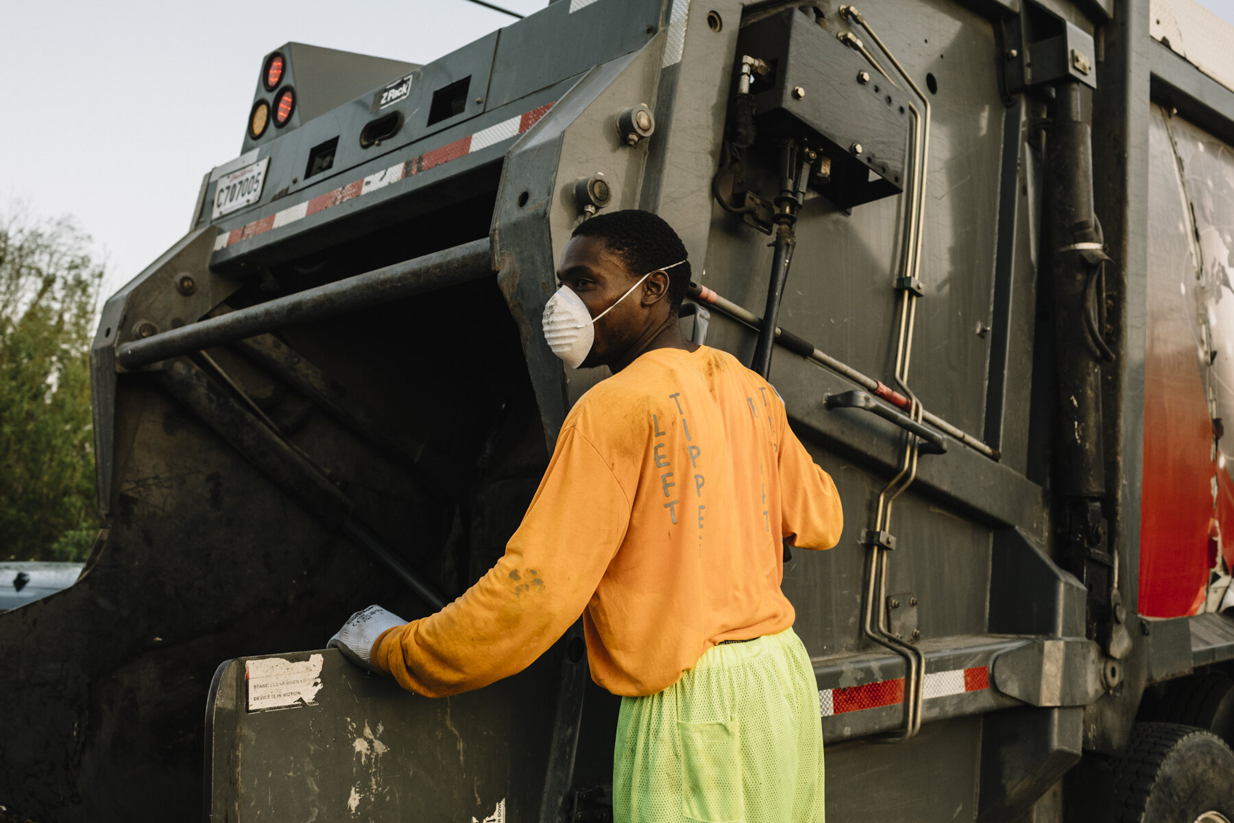  New Orleans, LA - March 24, 2020 - Bryan Bowman empties residential garbage cans into the back of a Metro Service Group truck in the 7th Ward of New Orleans. His employer has begun furnishing extra rubber gloves, facemasks, and handkerchiefs to thei