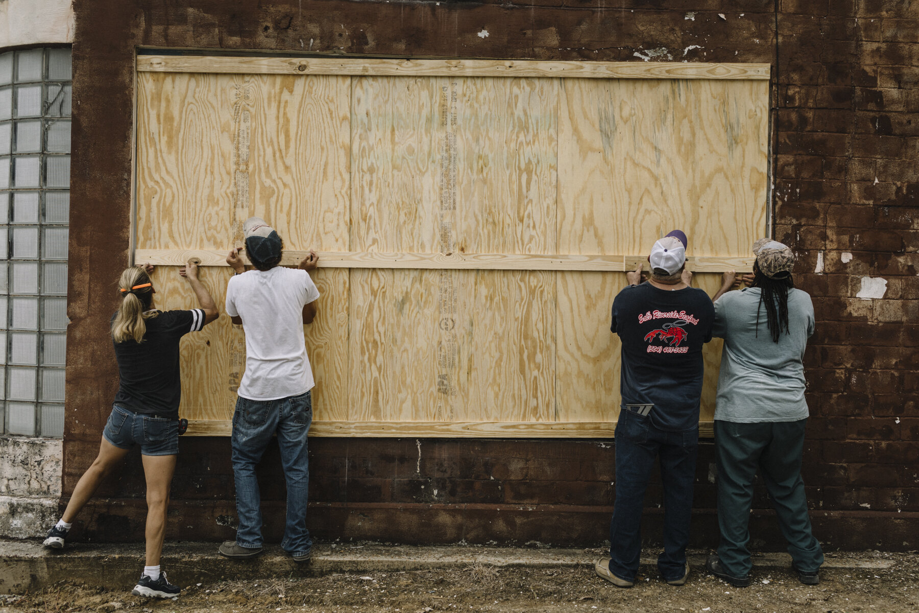  NYTSTORM - Abbeville, LA - August 25, 2020 - Local residents finish boarding up windows at an auto shop near downtown Abbeville as the first waves of rain begin to fall in advance of Tropical Depression Marco's arrival 