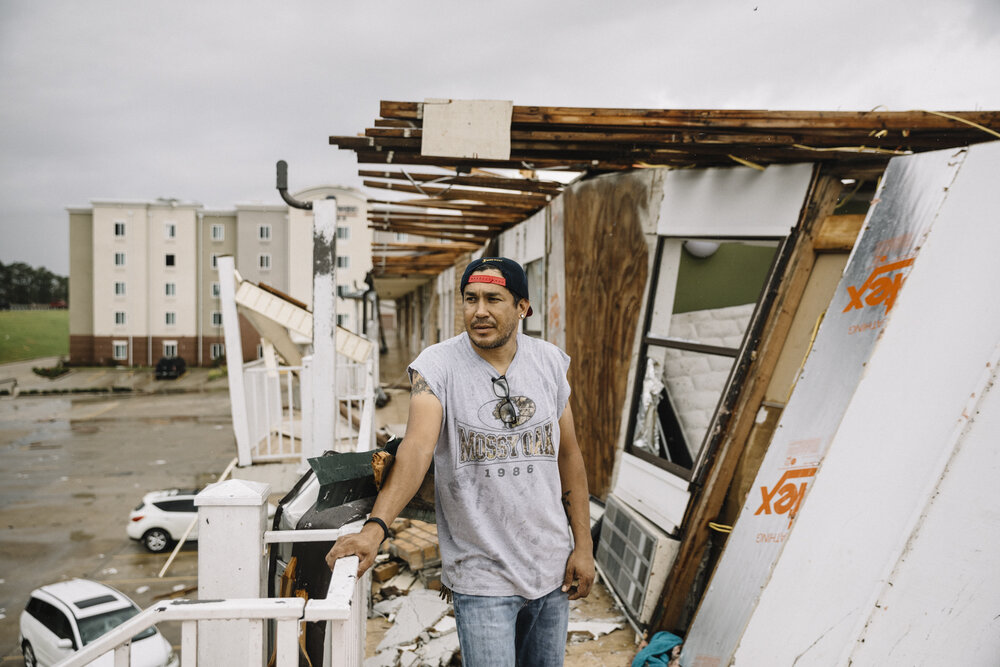  NYTSTORM - Lake Charles, LA - August 28, 2020 - Javier Palacias (43) stands outside the collapsed wall of his apartment at a Motel 6 where he's lived for the past six years while performing property maintenance. The entire roof of the building was r