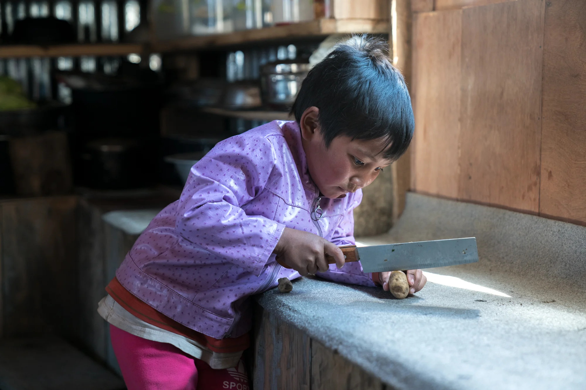 Young girl cutting a potato- Langtang, Nepal