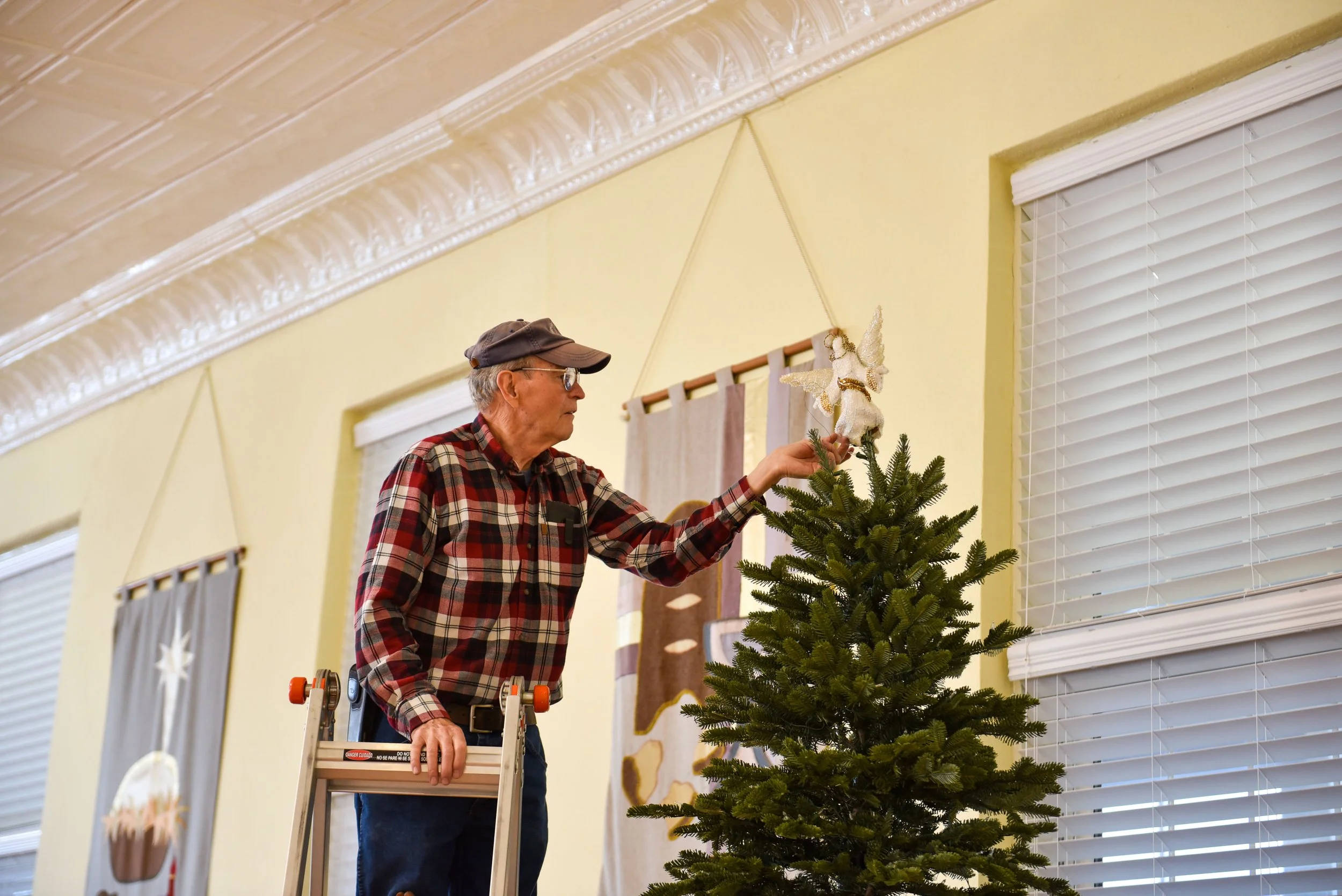  Roger Eibest sets an angel on the top of the tree. 