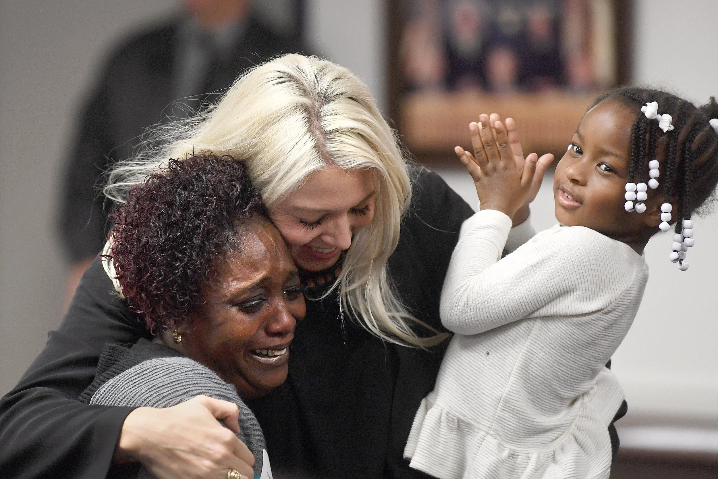Shalonda Robinson, left, cries tears of joy while being hugged by attorney Amanda Buenger during Brazos Valley Adoption Day on Wednesday, Nov. 14, 2018, in Bryan, Texas. Buenger is holding Robinson's three-year-old granddaughter, Ju'Torrah, one of four children Robinson adopted during Brazos Valley Adoption Day. (Laura McKenzie/The Eagle)