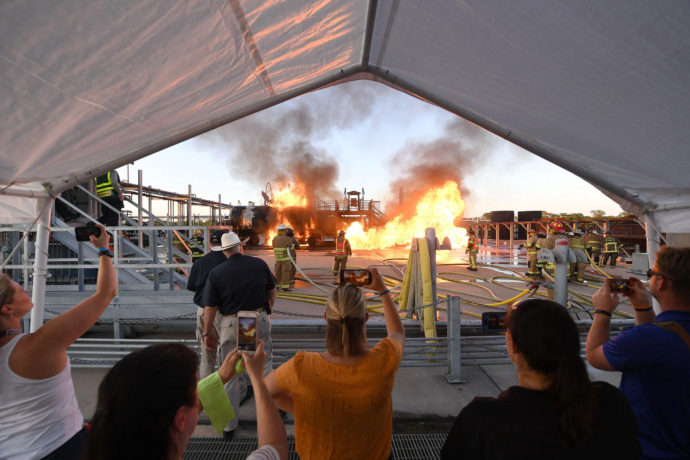 Spectators stand at a safe distance as a structure burns Wednesday, July 24, 2019, during the 90th Annual Municipal Fire School Public Demonstration Night at the TEEX Brayton Fire Training Field in College Station, Texas. (Laura McKenzie/The Eagle)