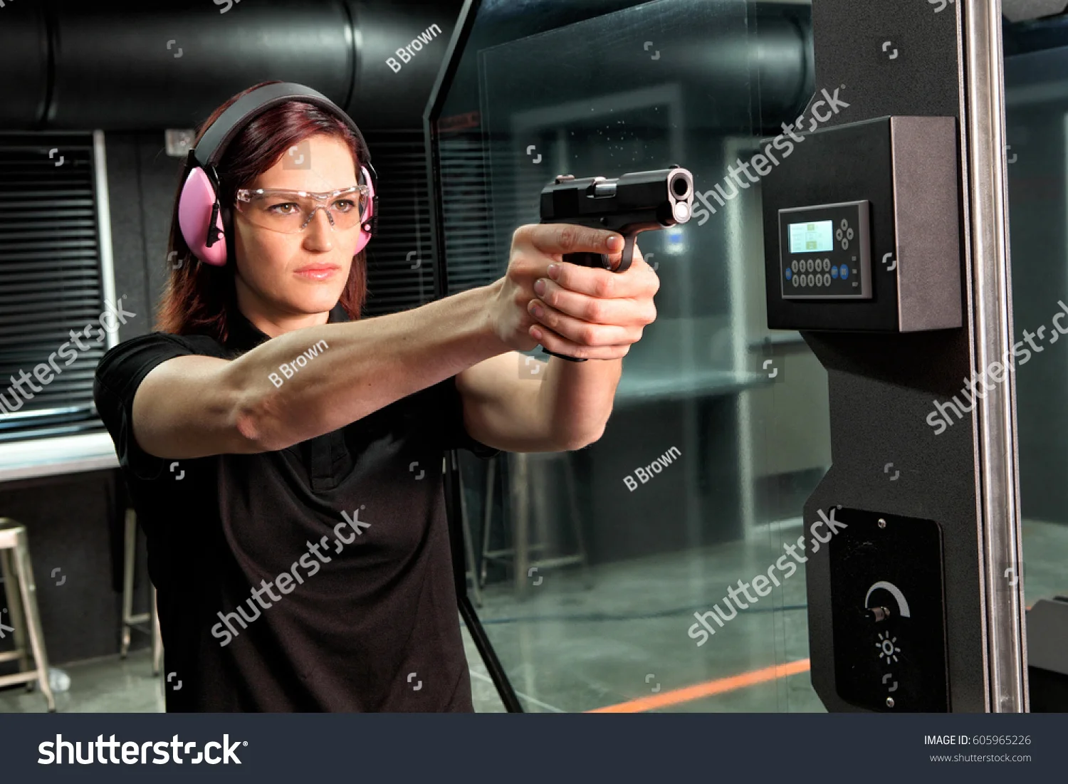 stock-photo-a-woman-firing-a-hand-gun-at-an-indoor-gun-range-605965226.jpg
