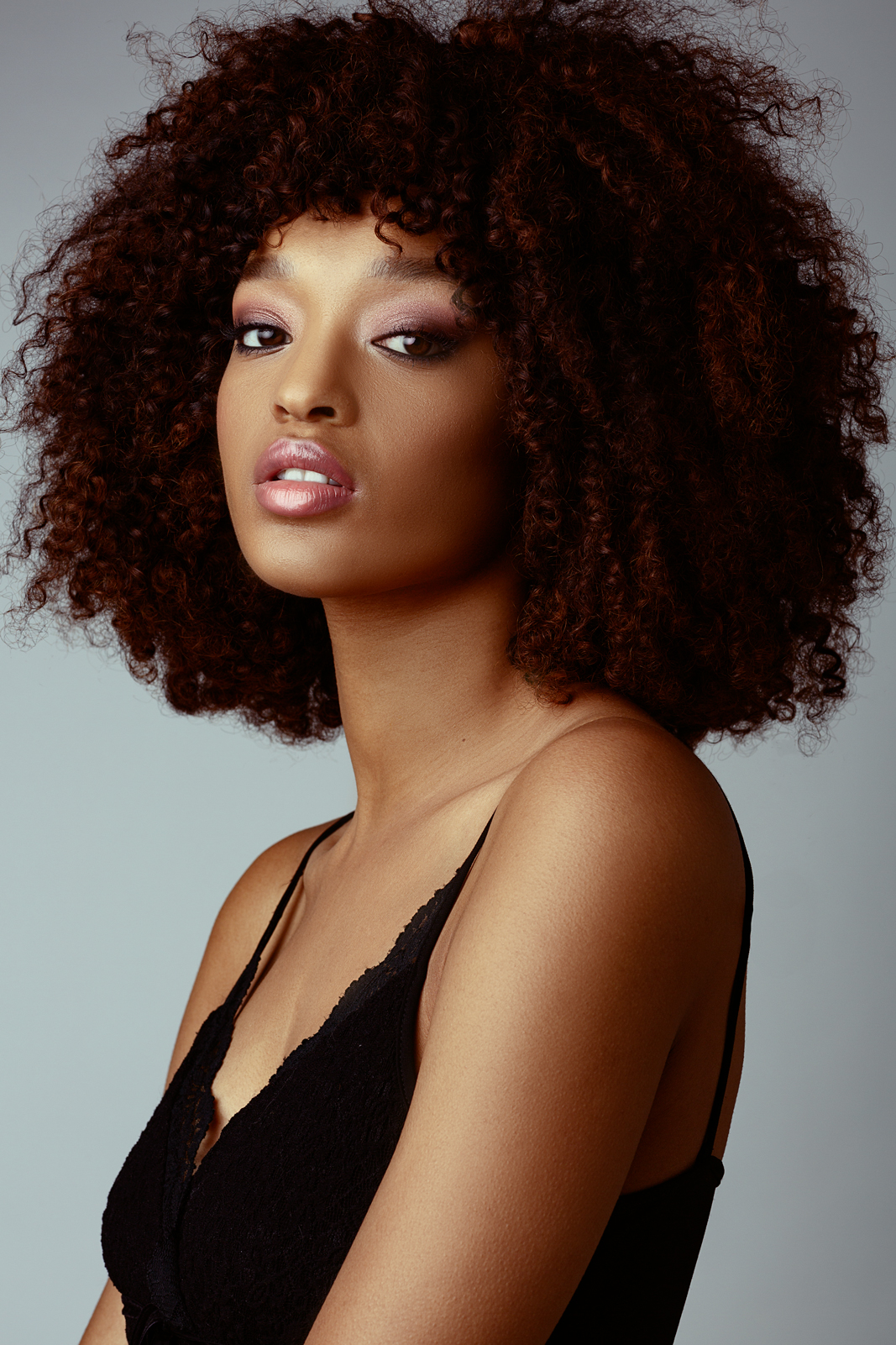 Portrait of a woman with curly hair and a black top, looking at the camera.