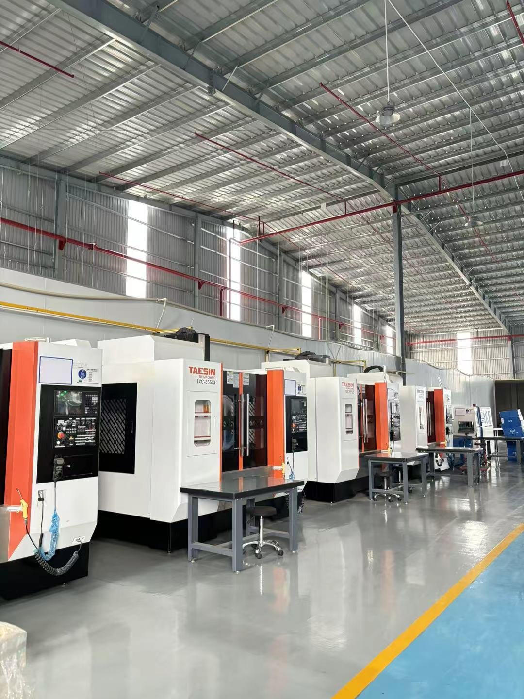 Factory with multiple CNC machines aligned in a spacious, well-lit industrial workshop.