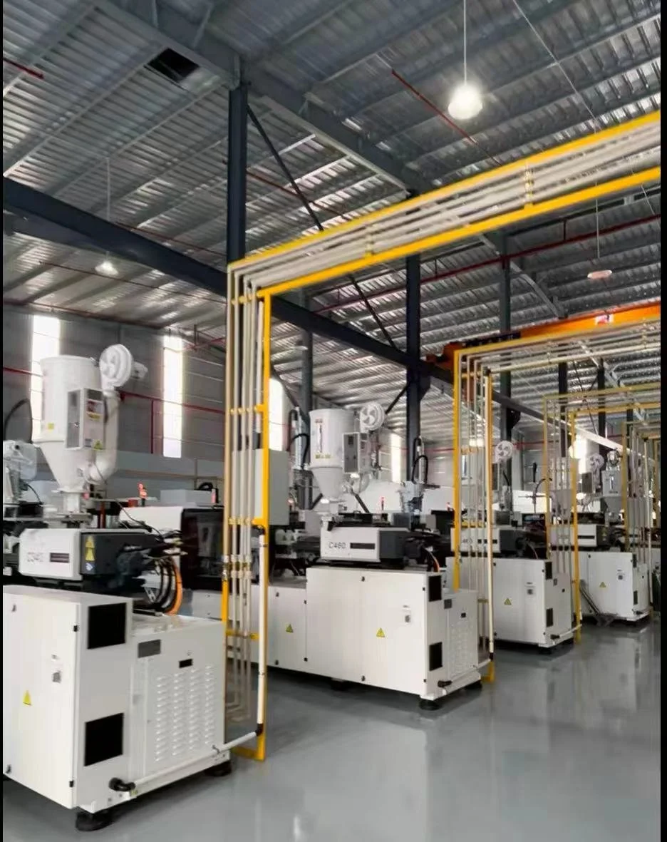 Row of industrial machines in a manufacturing plant with yellow safety barriers and a high metal roof.