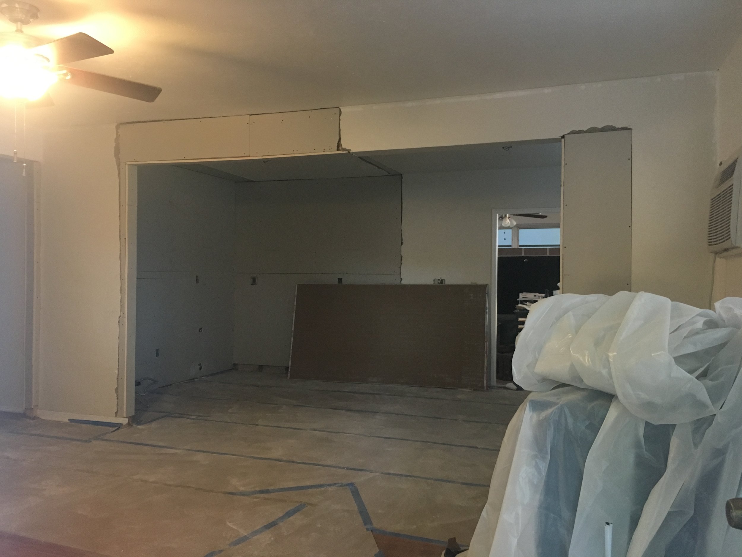  Once the new floors were installed, and electrical was completed, the drywall installers came in and patched up the walls. We removed the door to the left of the back wall as well as the small window to give us more wall and counter space. Since bot