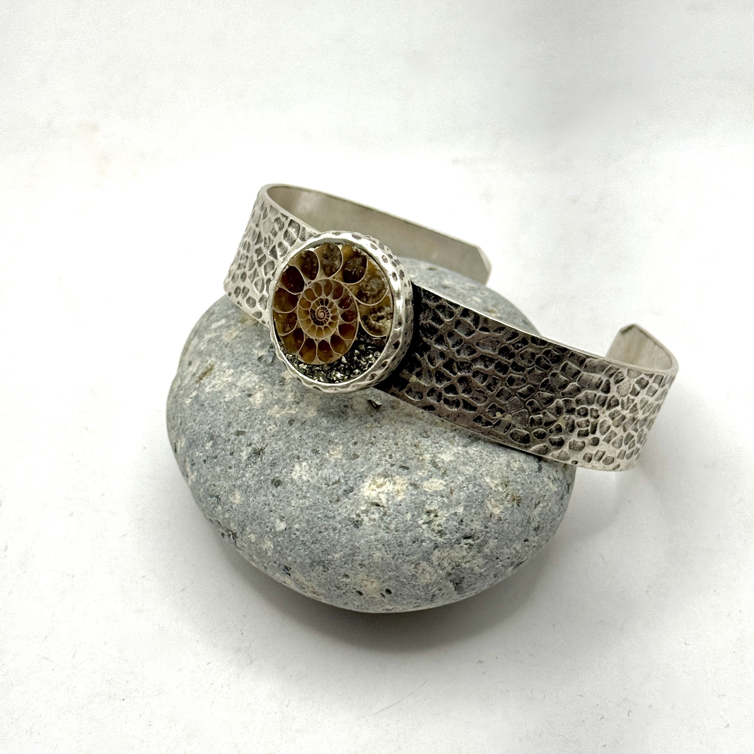1/2” hammered silver plate adjustable band with 3/4” circle holding Ammonite Fossil and pyrite chips
