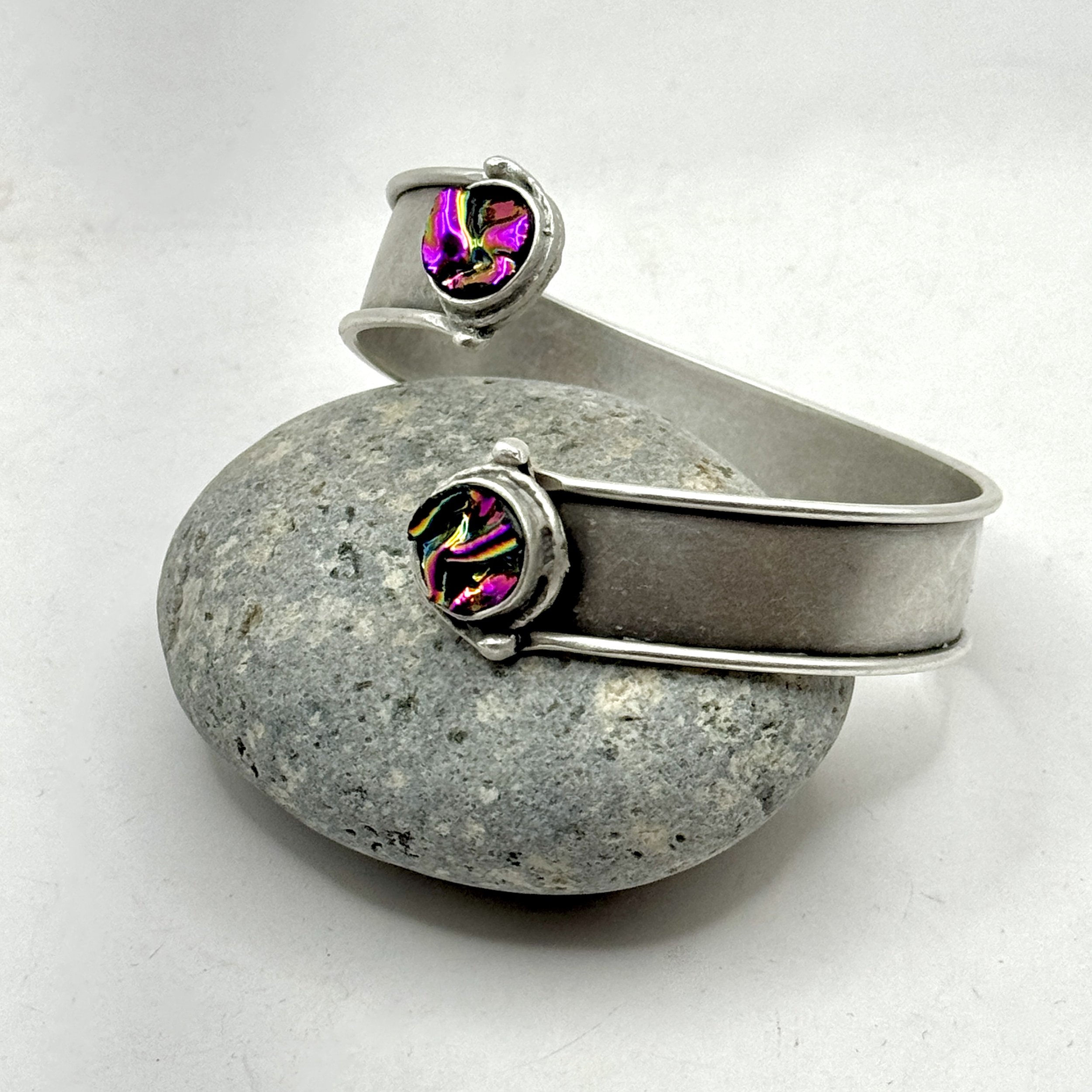 1/2” wide wrap silver plated bracelet with two circles of pink/purple dichroic glass.