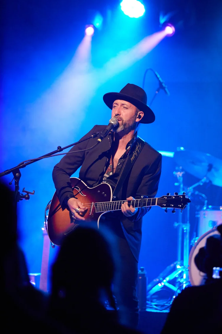 Justin Froese singing and playing acoustic guitar onstage