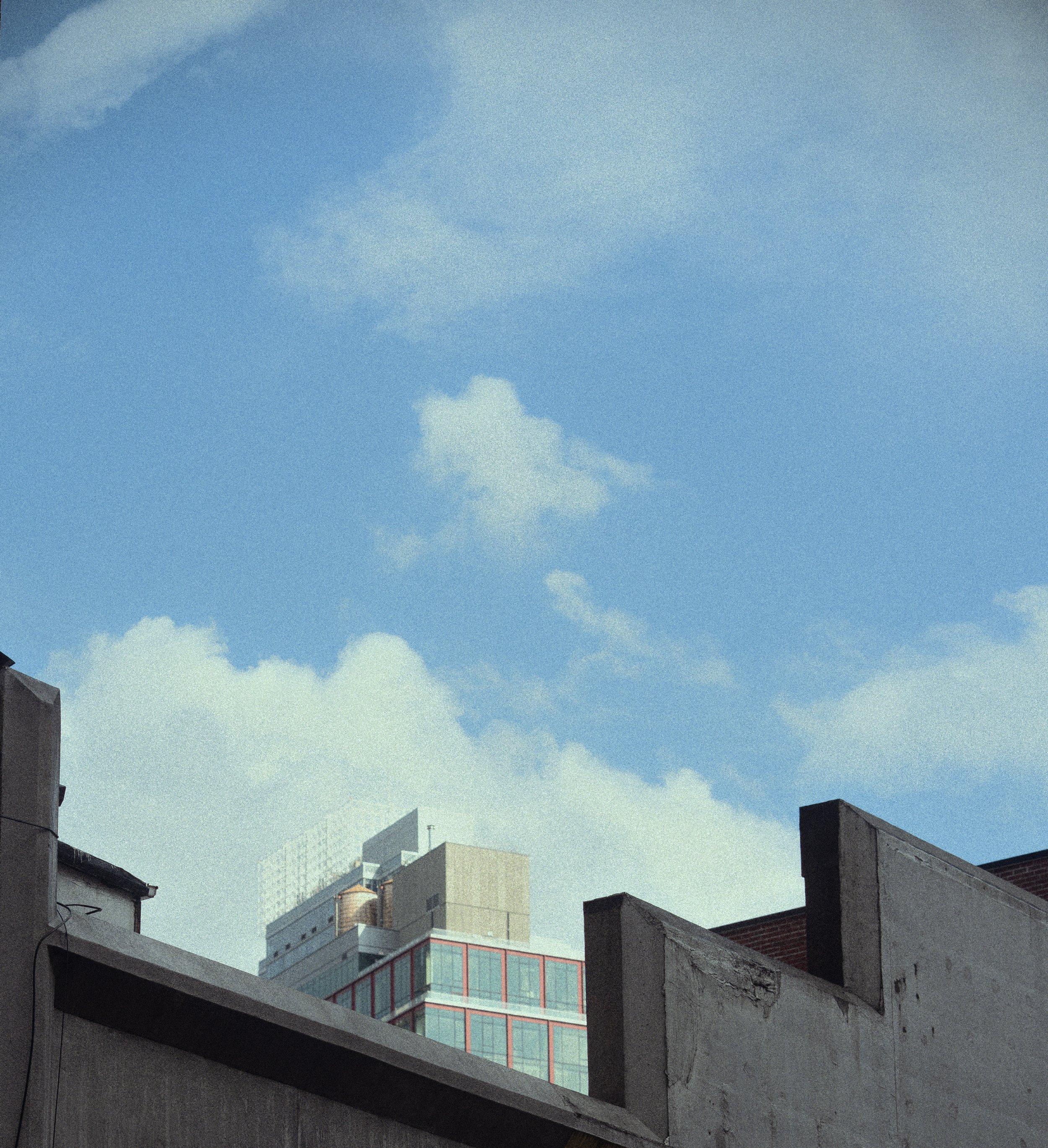 Cityscape with buildings and a blue sky with scattered clouds.