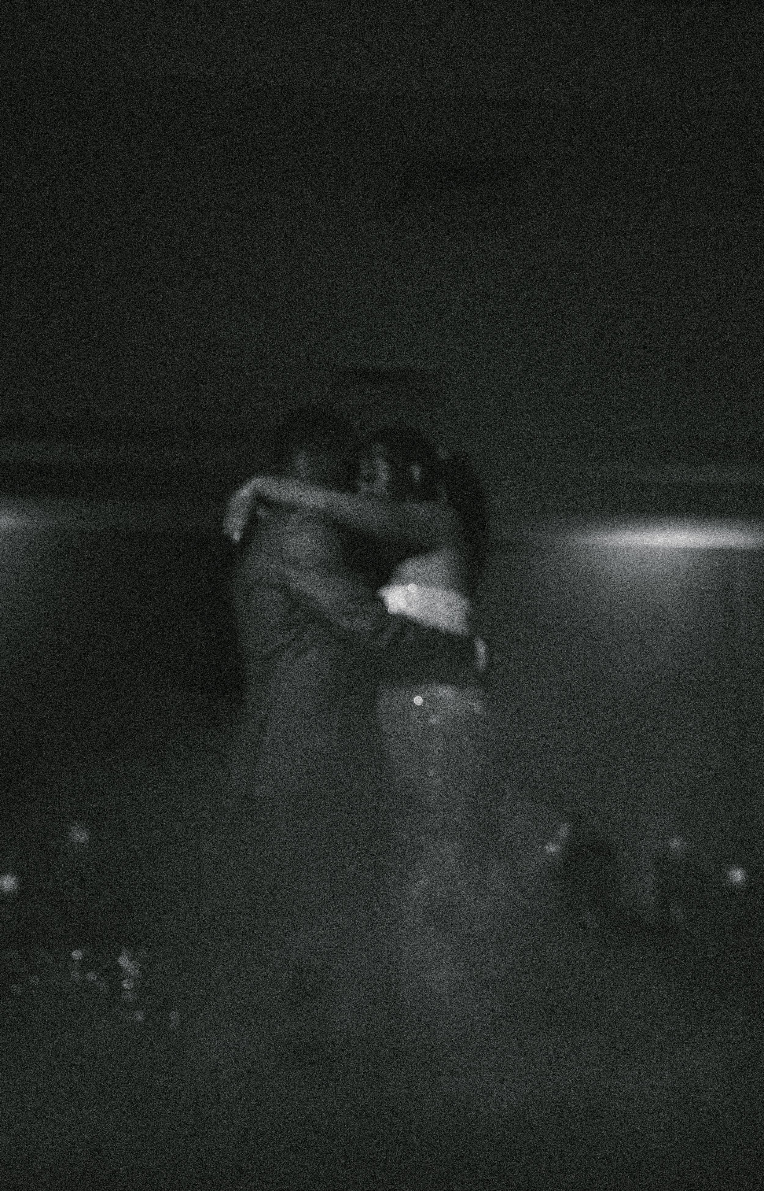 Black and white photo of a couple dancing closely together in a dimly lit setting.