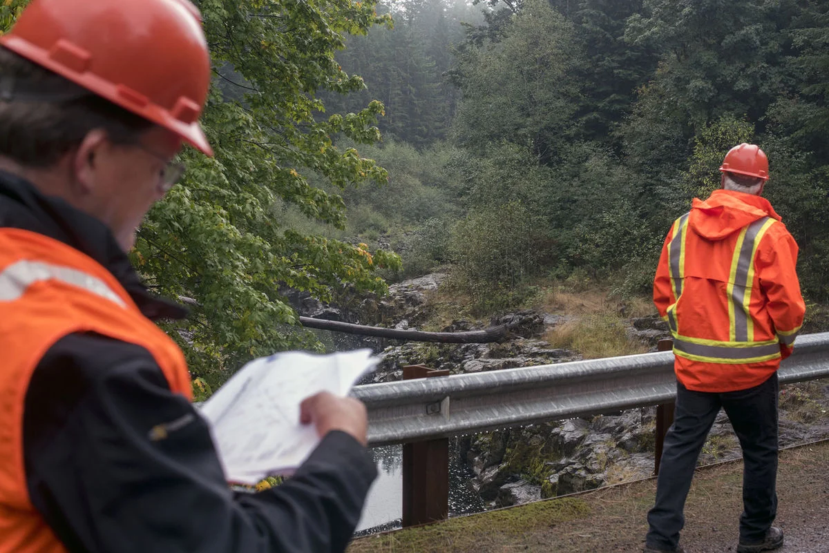 Project designer Keith Moen of HDR Engineering, left, walks across a bridge where the proposed dam would be located. The area in the background is the upstream side of the proposed dam. Graham Perednia / gperednia@chronline.com