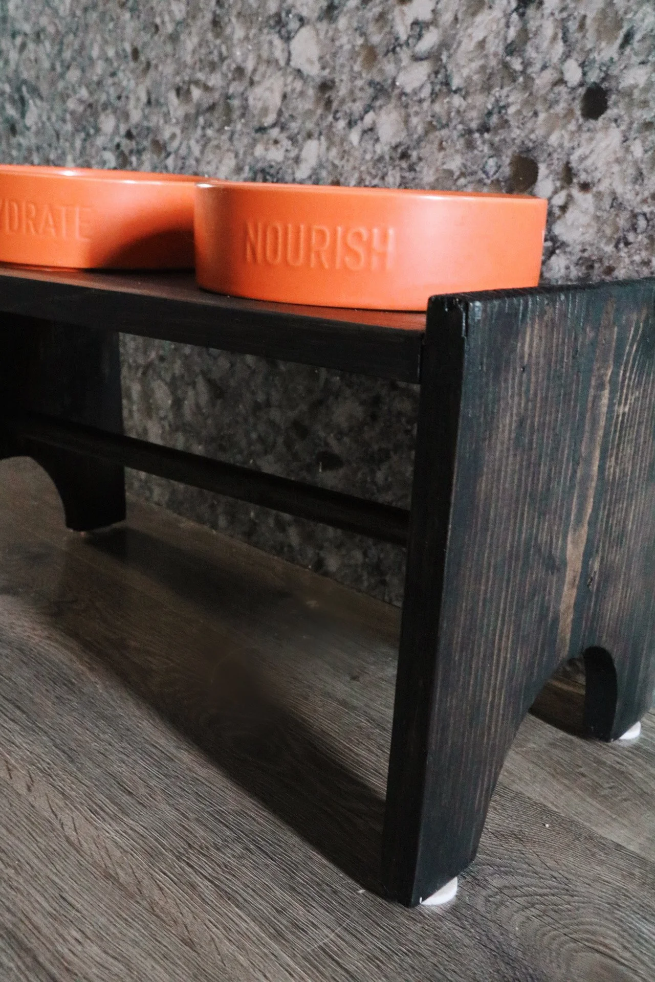 Elevated dog bowl station with orange food and water bowls