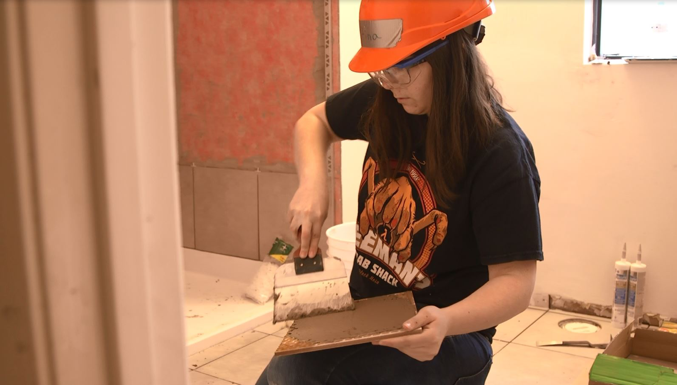 Mohawk student laying tiles