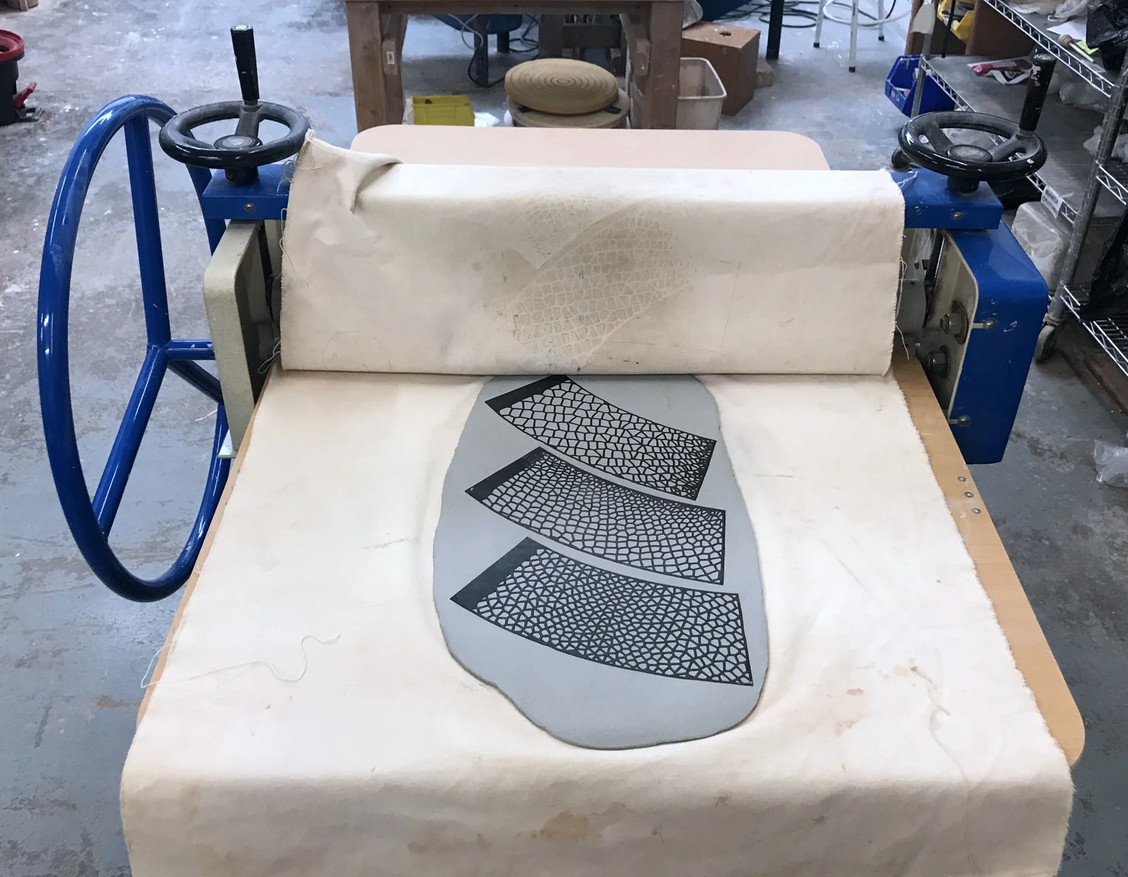 Pressing templates into a slab of clay with a slab roller.