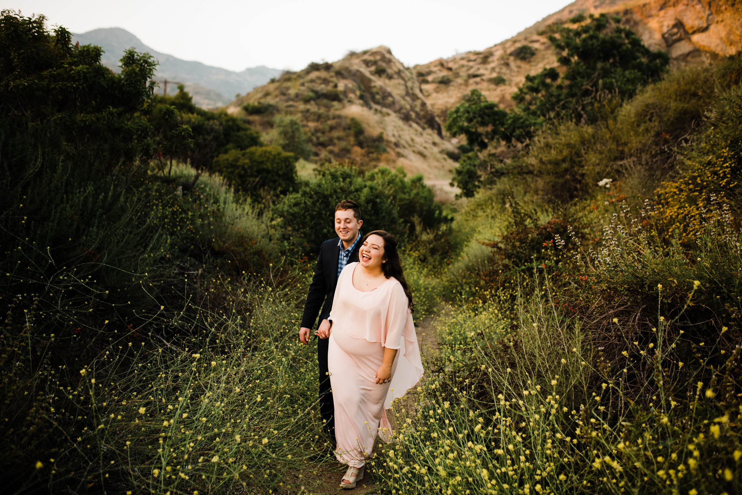 Couple walking through wildflowers and mountains in Los Angeles, California for their adventurous engagement shoot