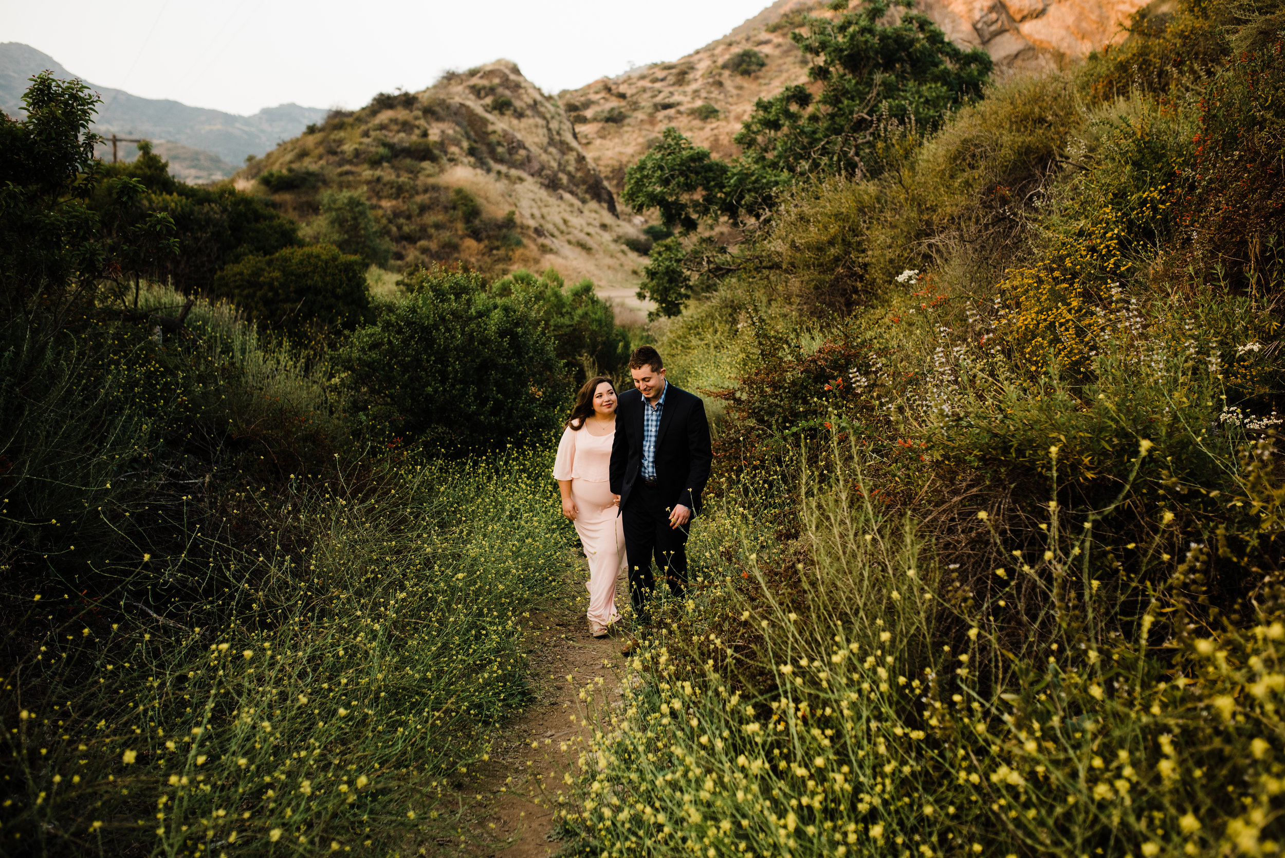 Couple walking through wildflowers and mountains in Los Angeles, California for their adventurous engagement shoot