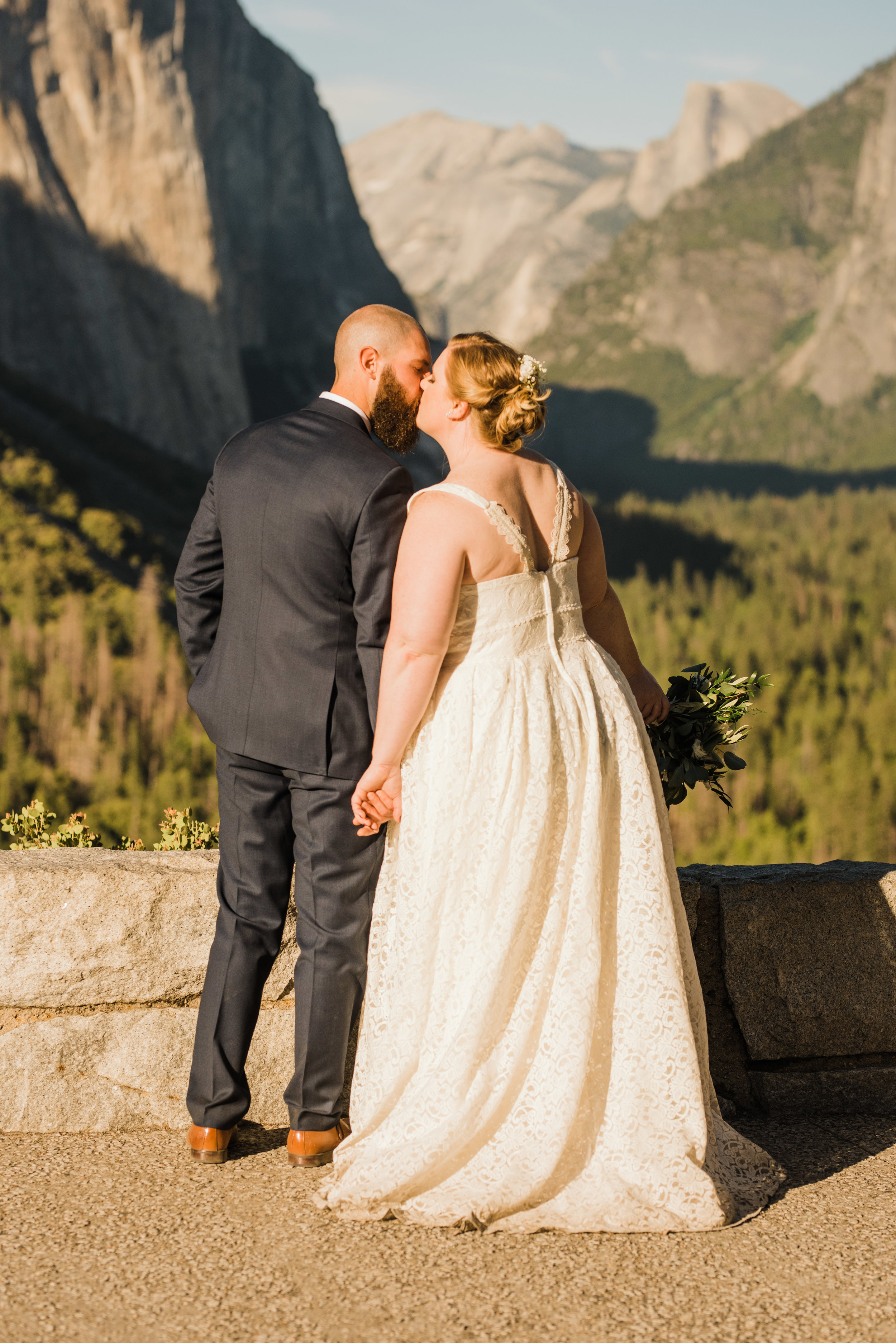 Bride and groom kiss in front of El Capitan and Half Dome in Yosemite National Park in the same spot that Ansel Adam once photographed: Tunnel View