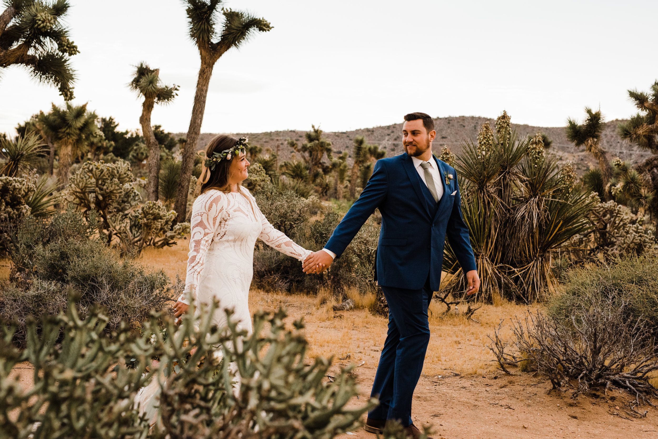 bride and groom walking through joshua tree