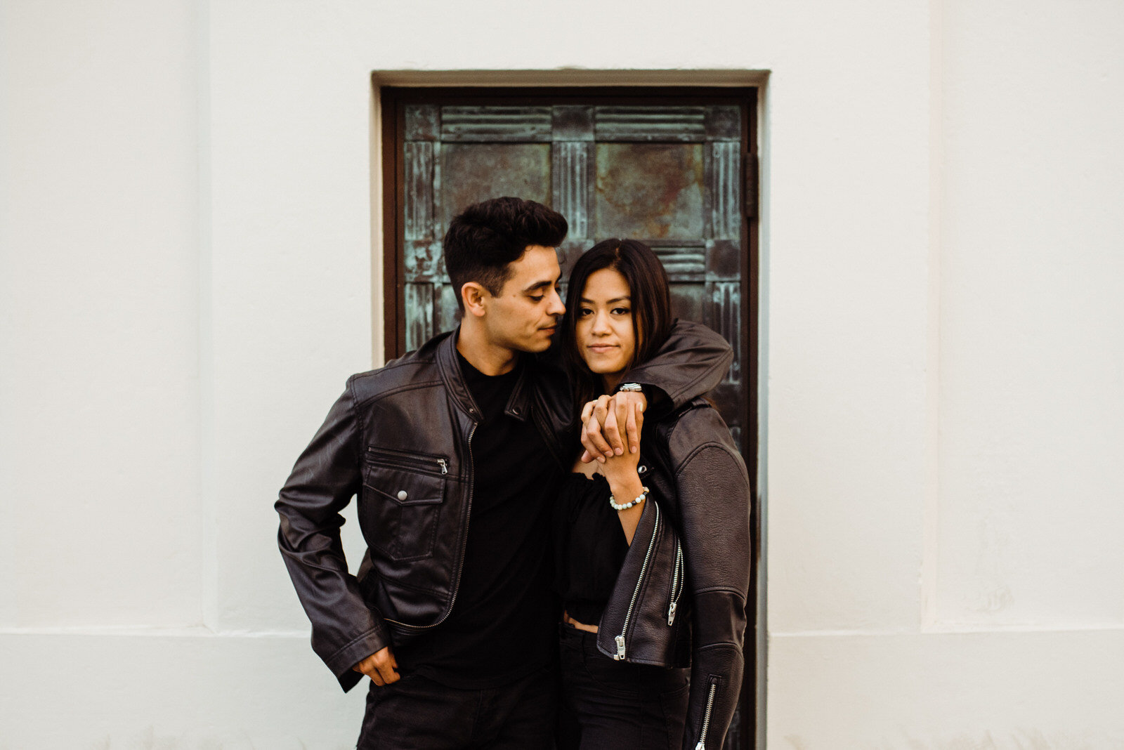Couple in all black pose in front of copper door at Griffith Observatory 