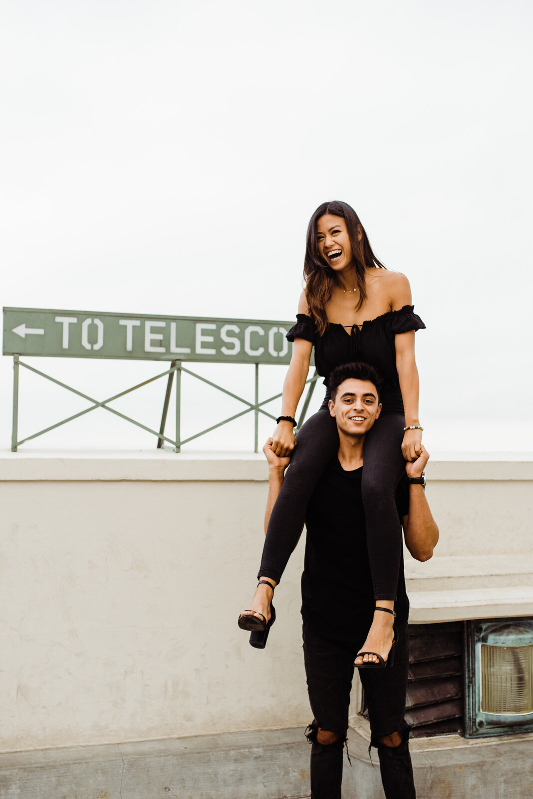 Girl on boy's shoulders during dark and moody engagement session