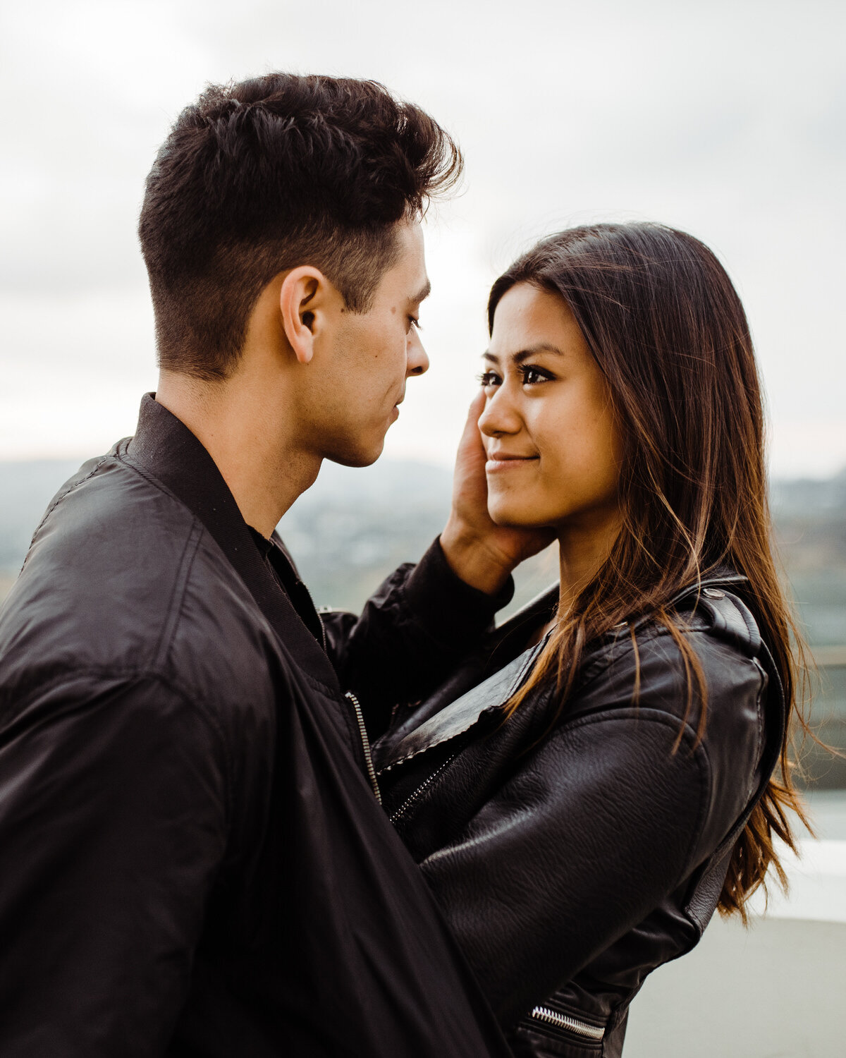 Couple Smiling at Each Other in Dark and Moody Engagement Photos at Griffith Observatory