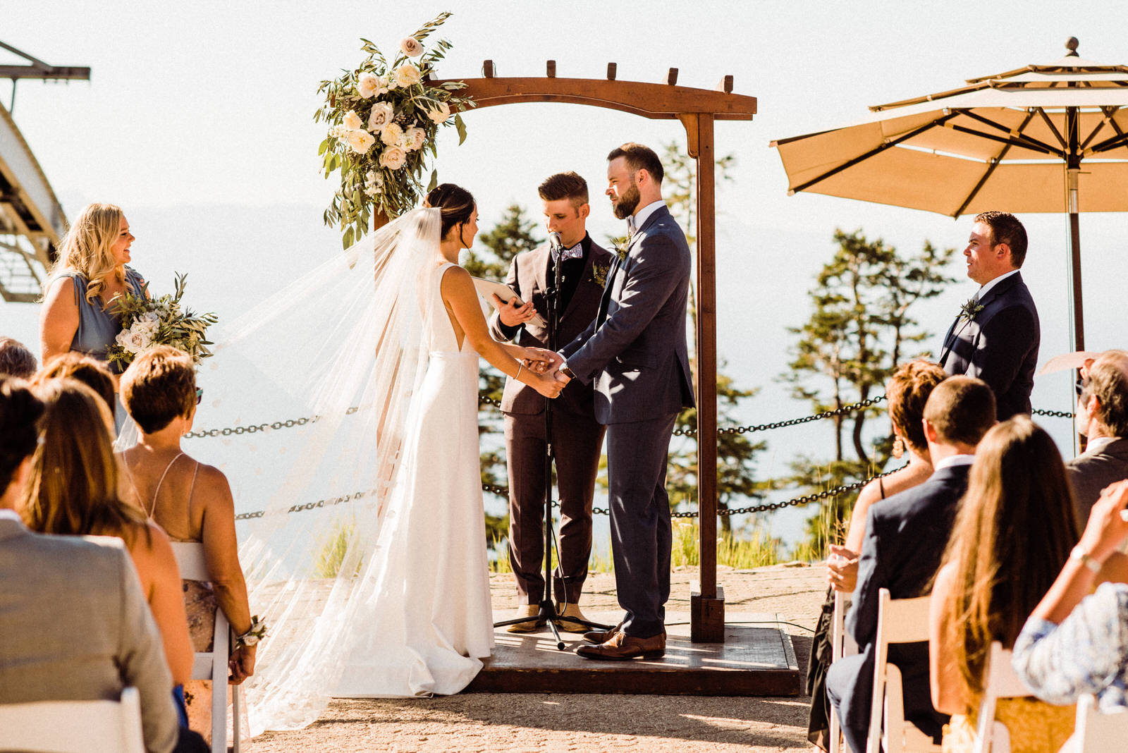 Bride and groom beneath wooden arch with white roses at Lakeview Lodge in South Lake Tahoe