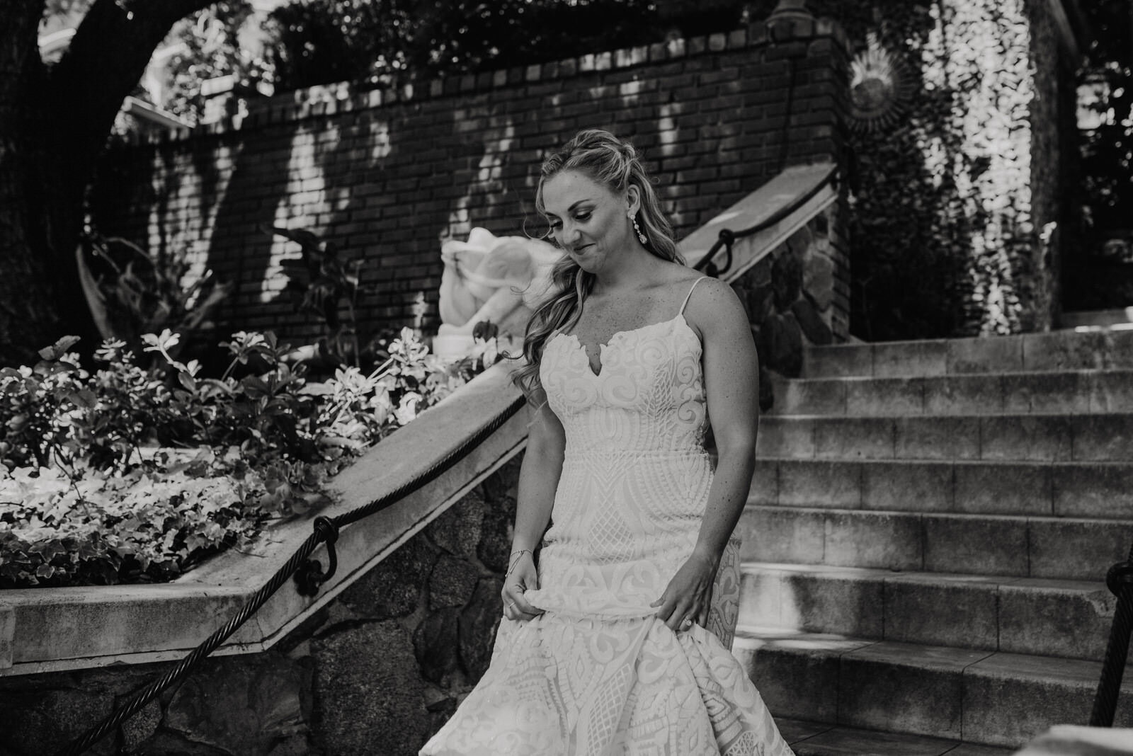 Black and white photo of bride in Hayley Paige dress on stone steps at Houdini Estate Wedding First Look | photo by Kept Record | www.keptrecord.com