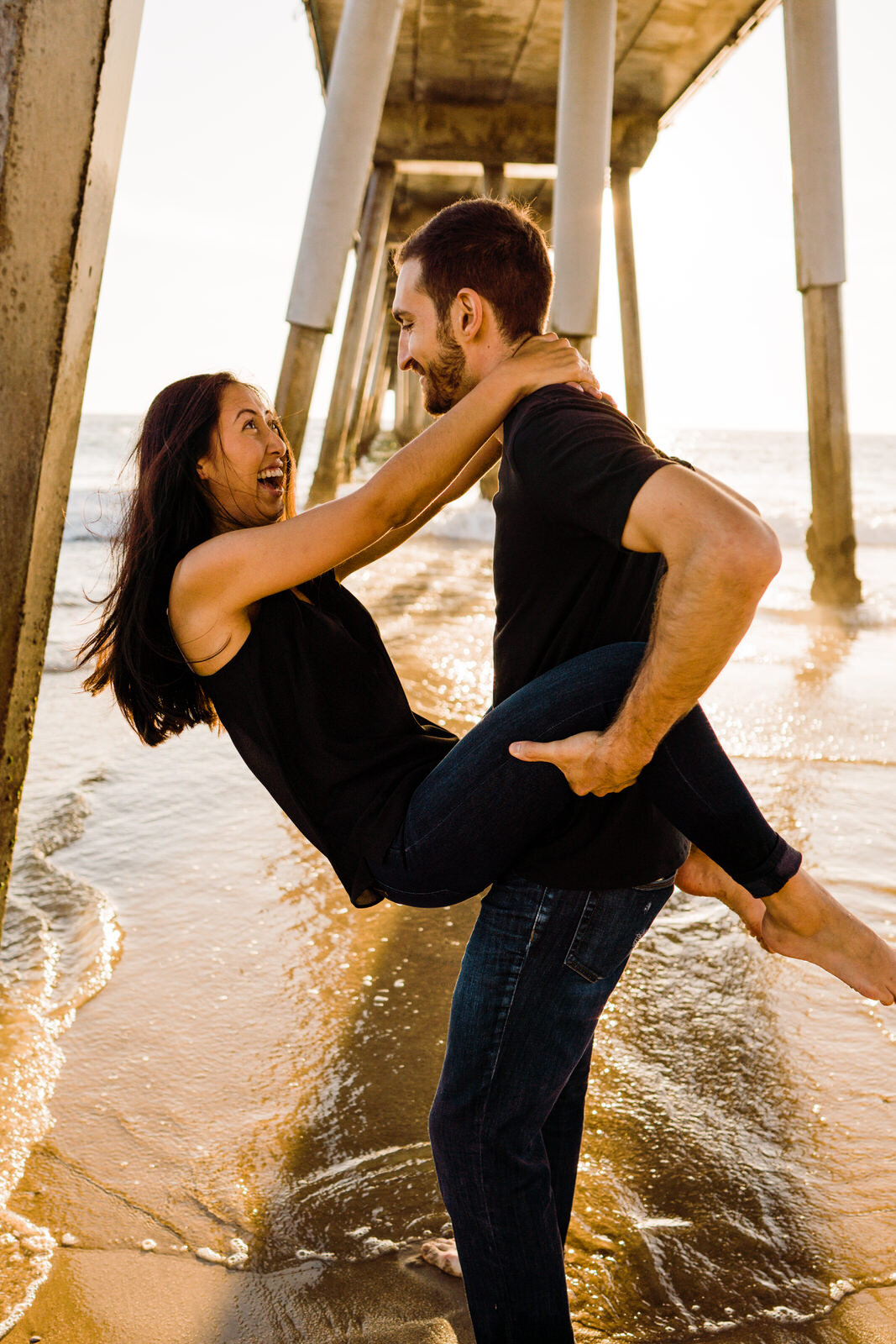 Playful, happy engagement photos under Hermosa beach pier