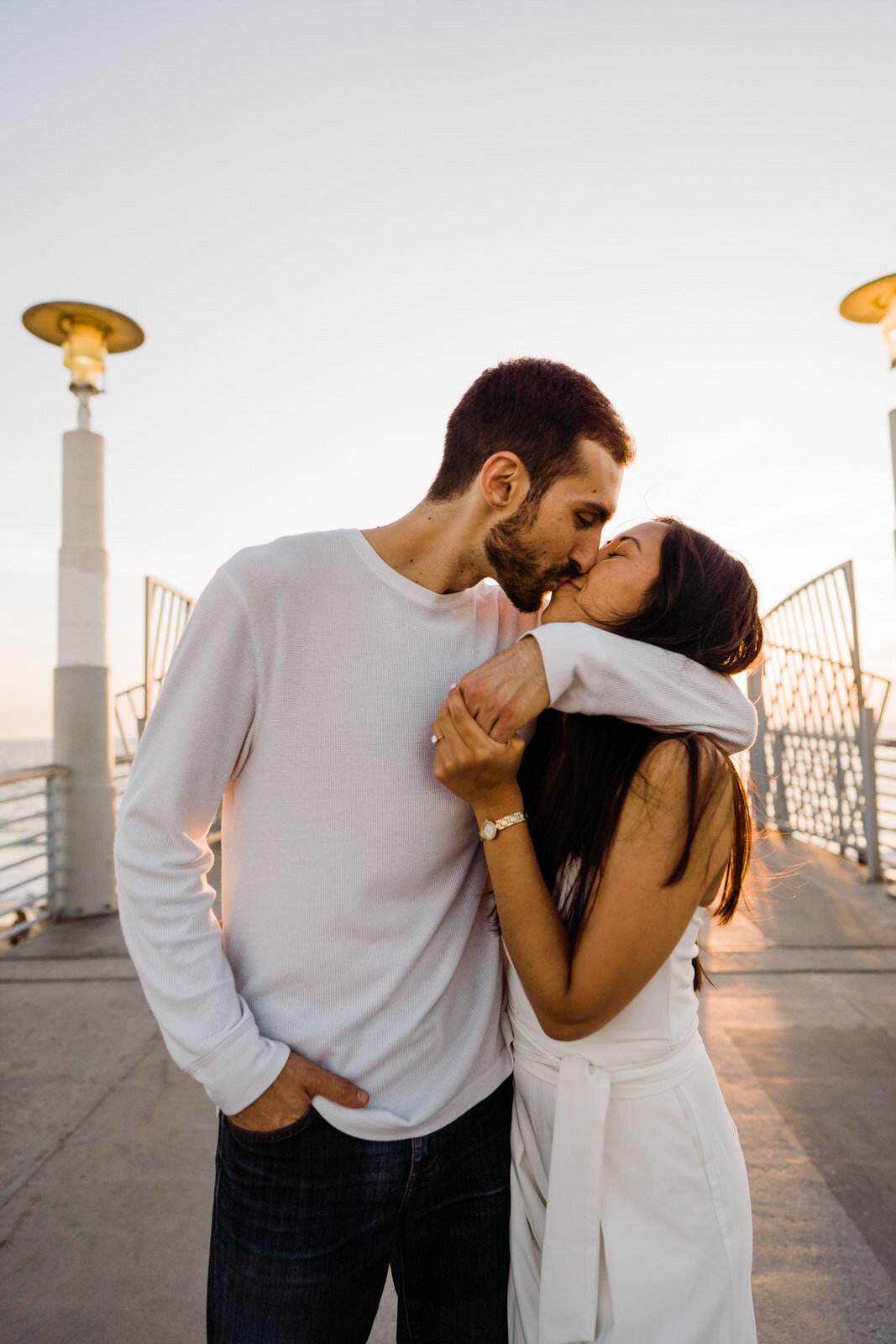 Engaged couple embraces on Hermosa beach pier