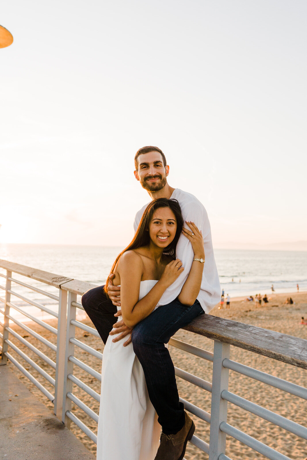 couple hugging at engagement session at hermosa beach pier sunset