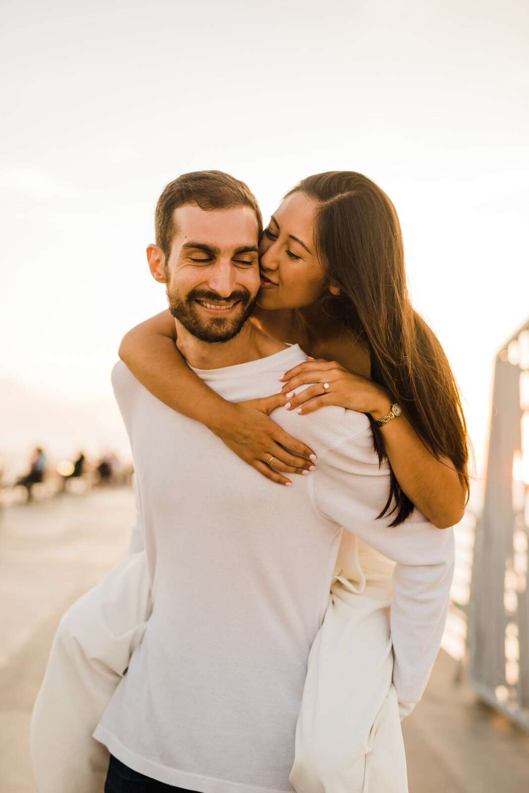 woman kisses man on cheek during piggyback ride at Hermosa Beach Pier