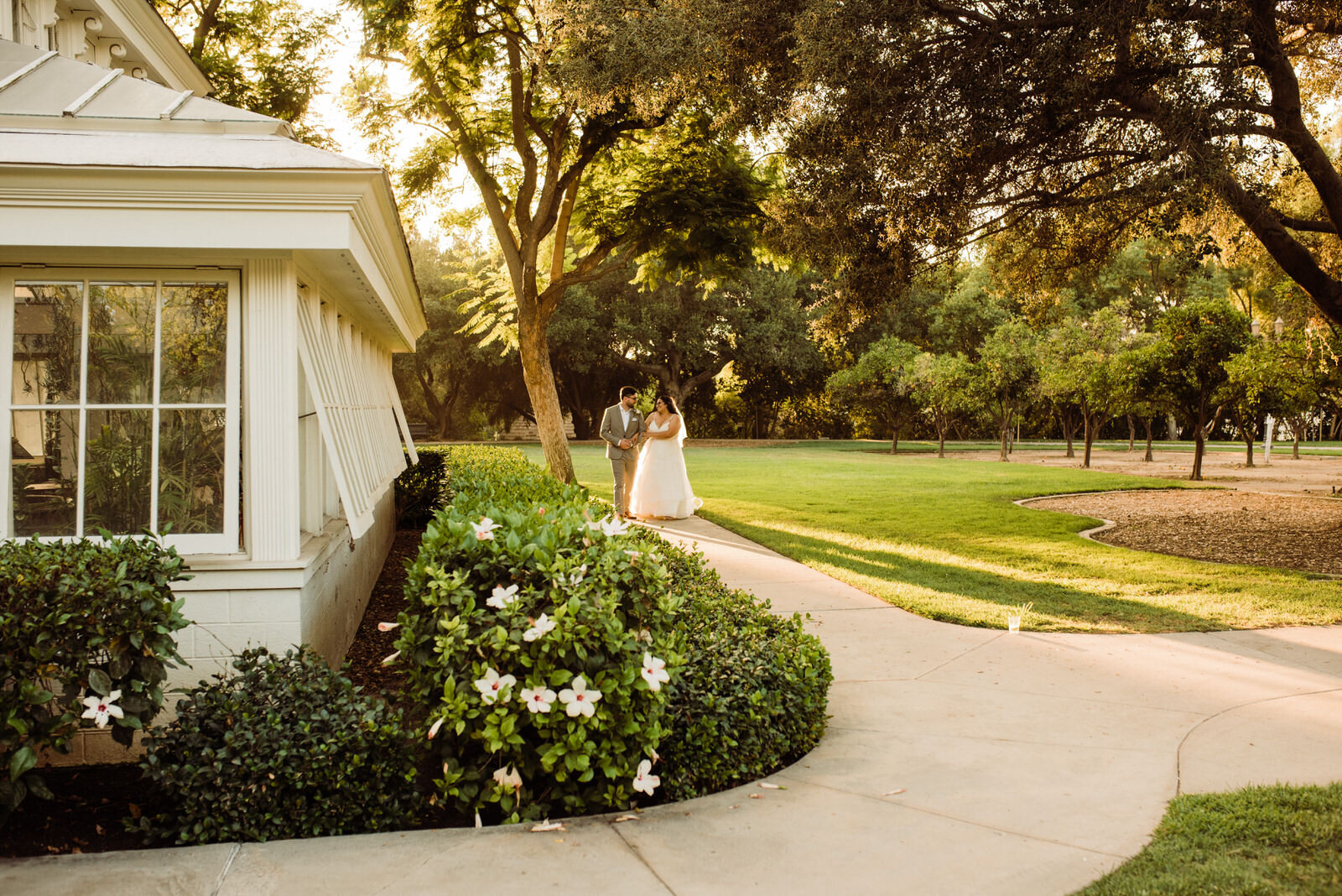 Husband and wife next to greenhouse at Heritage Park Plant Conservatory on wedding day in Santa Fe Springs