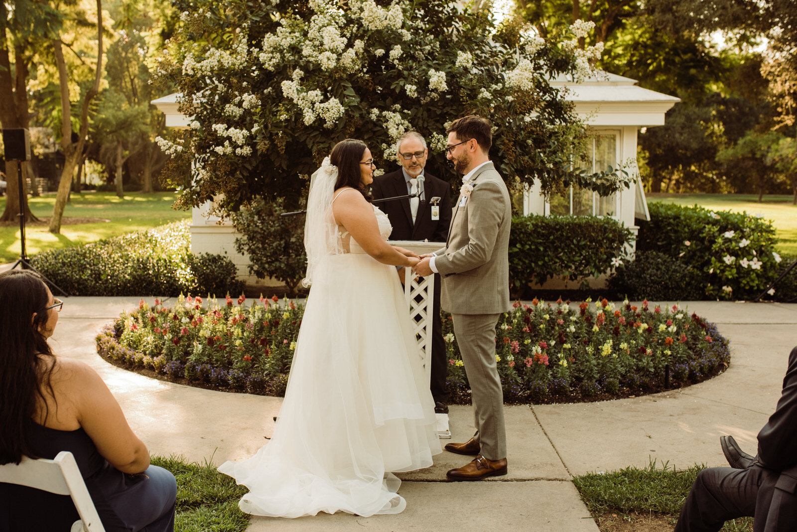 Couple exchanges vows in front of greenhouse at Heritage Park wedding