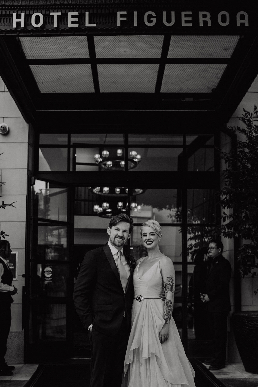 Newlyweds underneath Hotel Figueroa facade at modern, feminist wedding in Los Angeles