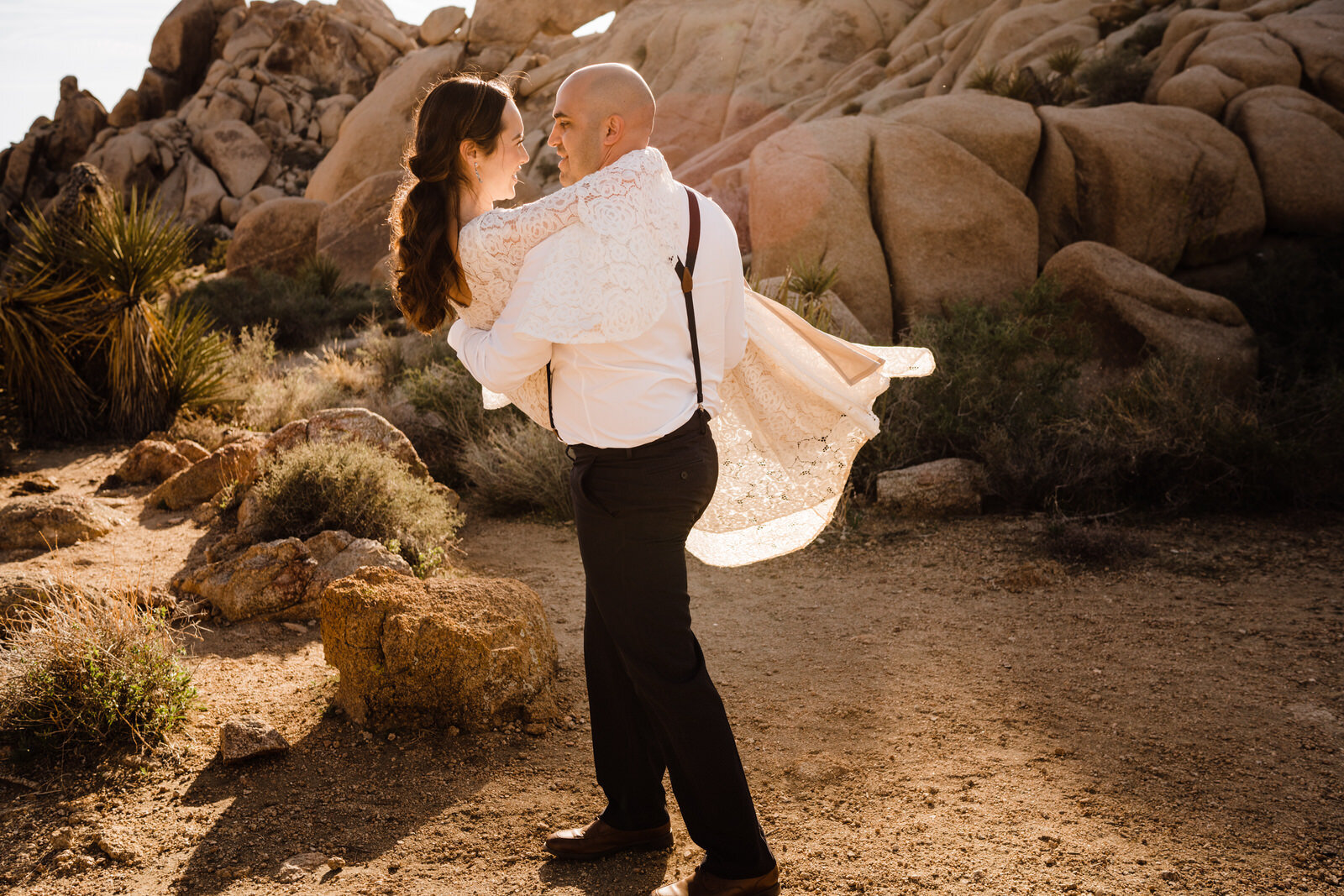 Groom spins bride in bohemian gown at Live Oak picnic area in Joshua Tree National Park elopement | adventurous, fun, warm wedding photos by Kept Record | www.keptrecord.com