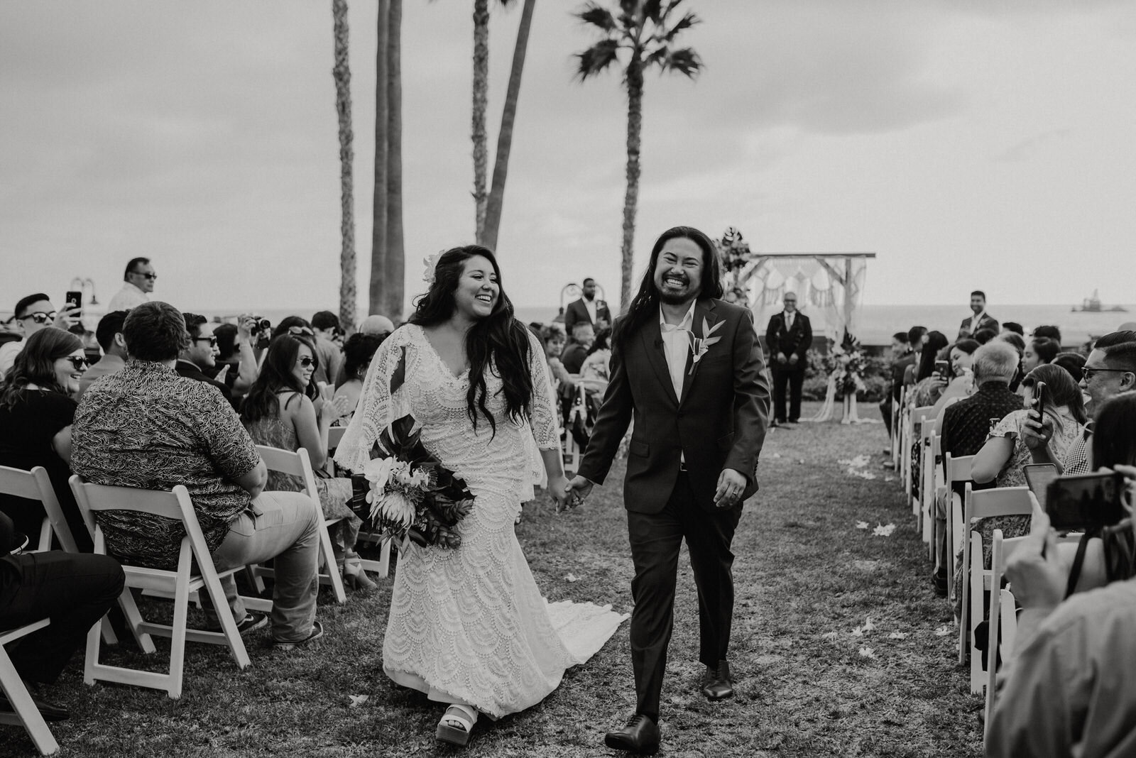 Black and white photo of bride and groom walking at Ole Hanson Beach Club ceremony