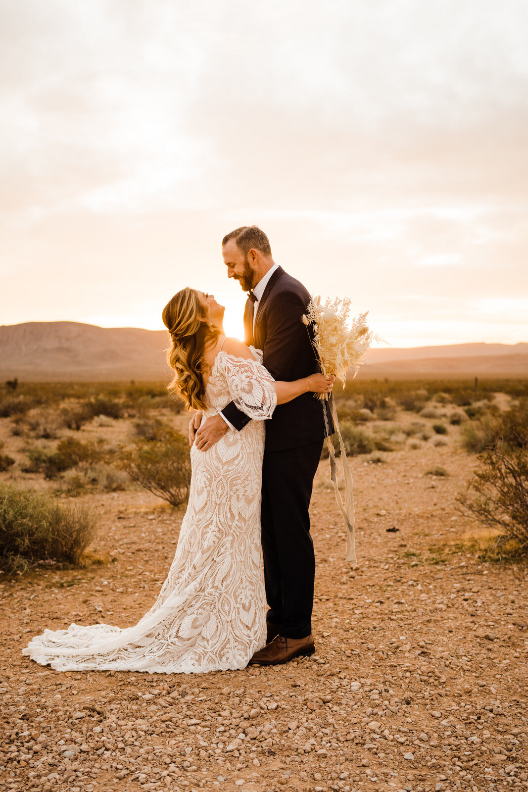 Bride and Groom Hug at Sunrise First Look at Seven Magic Mountains in Las Vegas, NV