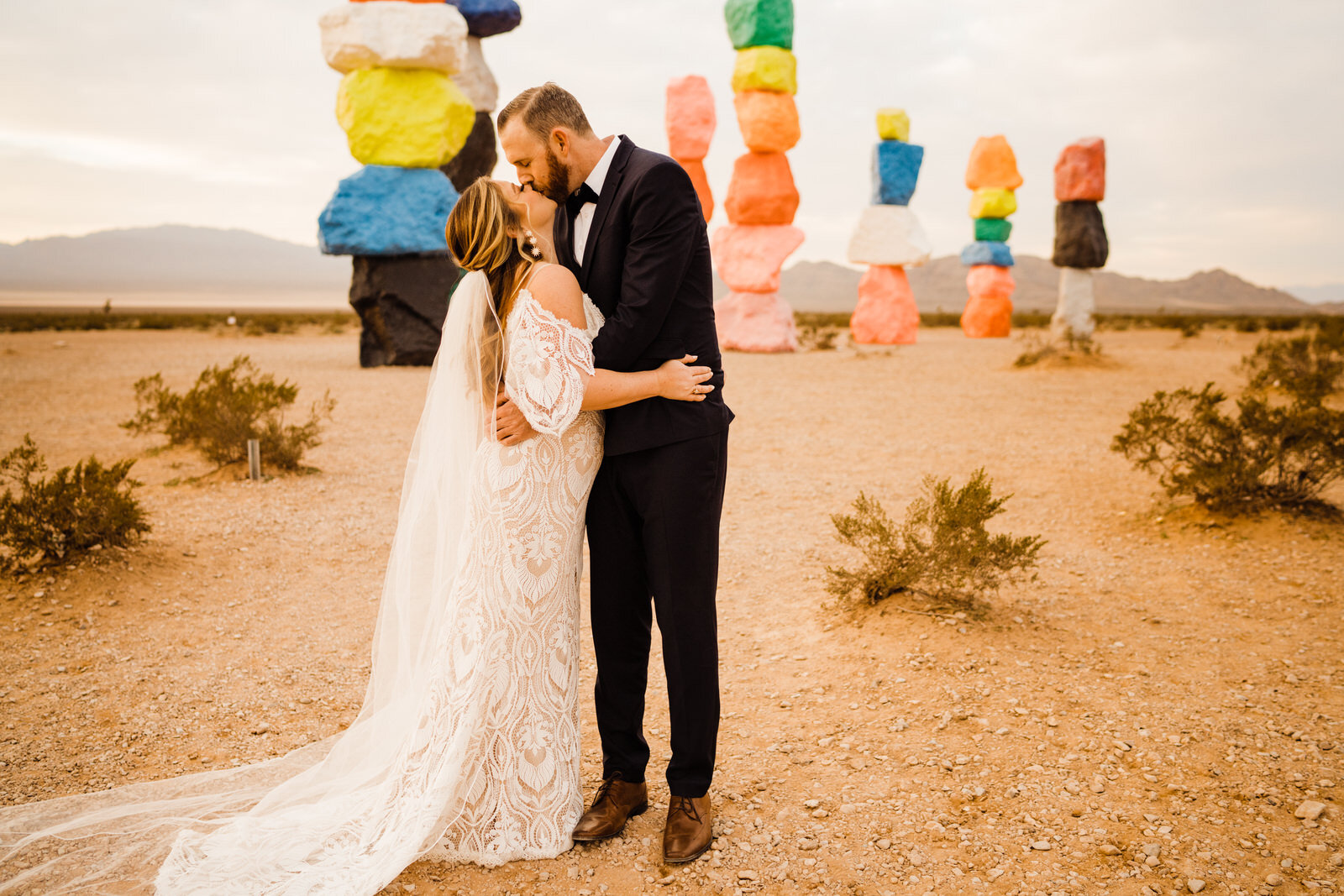 bride and groom kiss in front of seven magic mountains in Las Vegas, NV