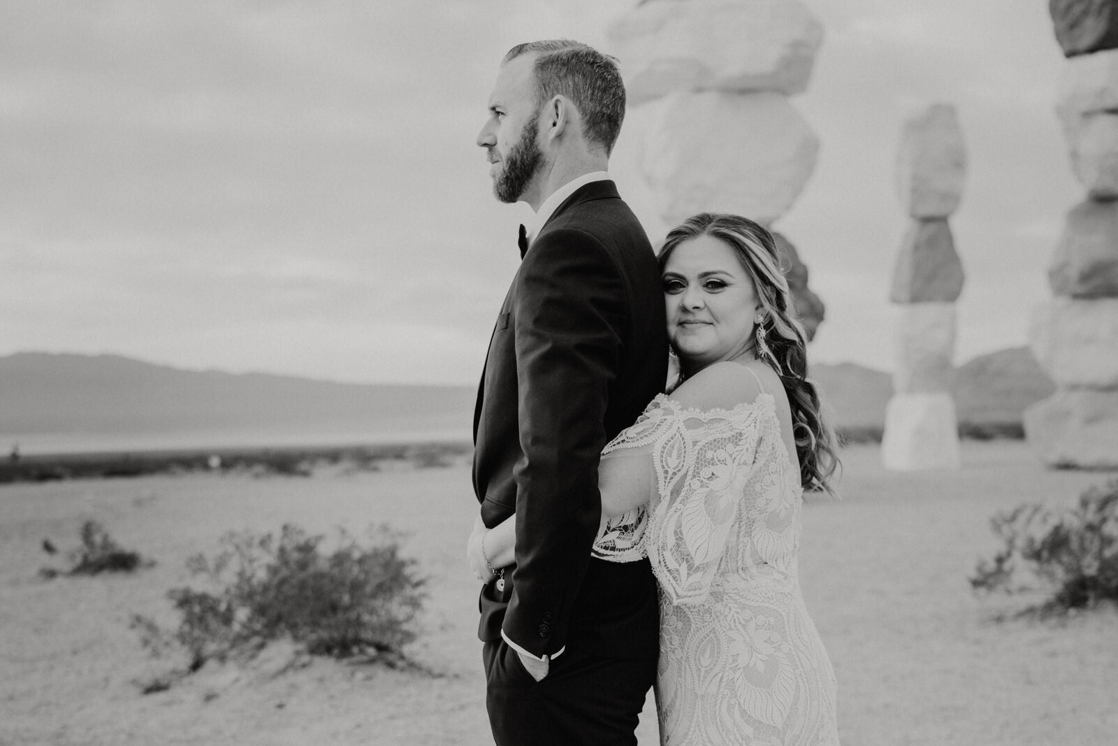 black and white photo of bride hugging groom as he looks at sunrise in Las Vegas, NV