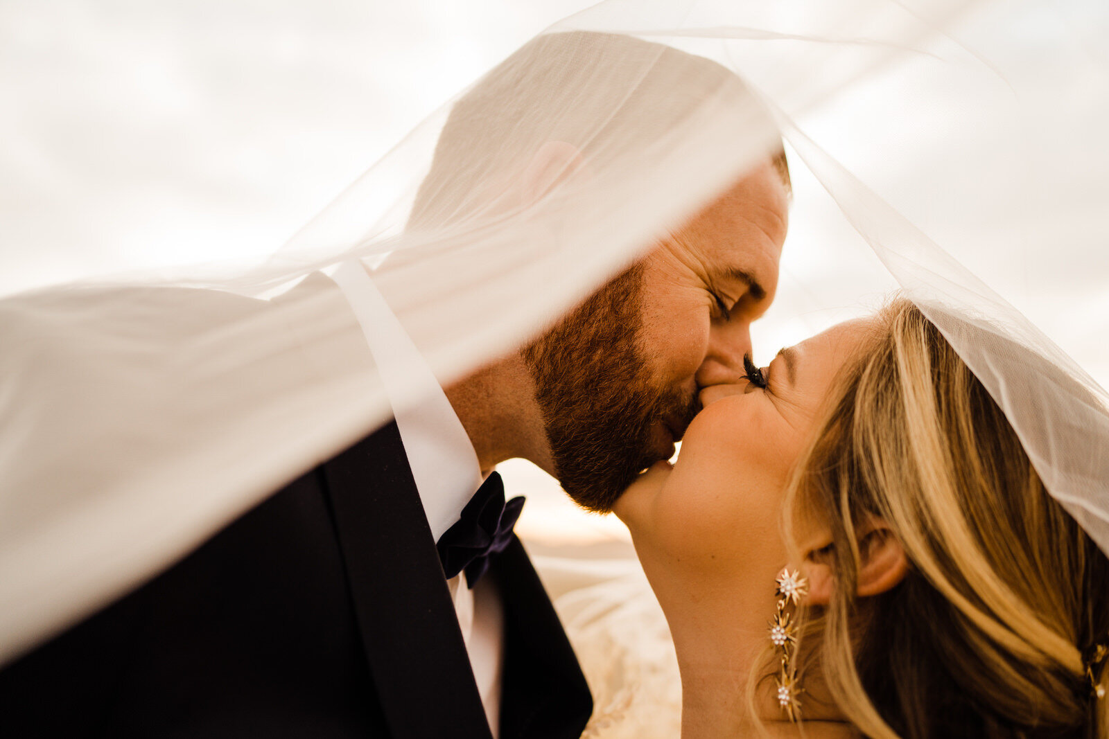 romantic photo of bride and groom kissing beneath veil in Las Vegas desert