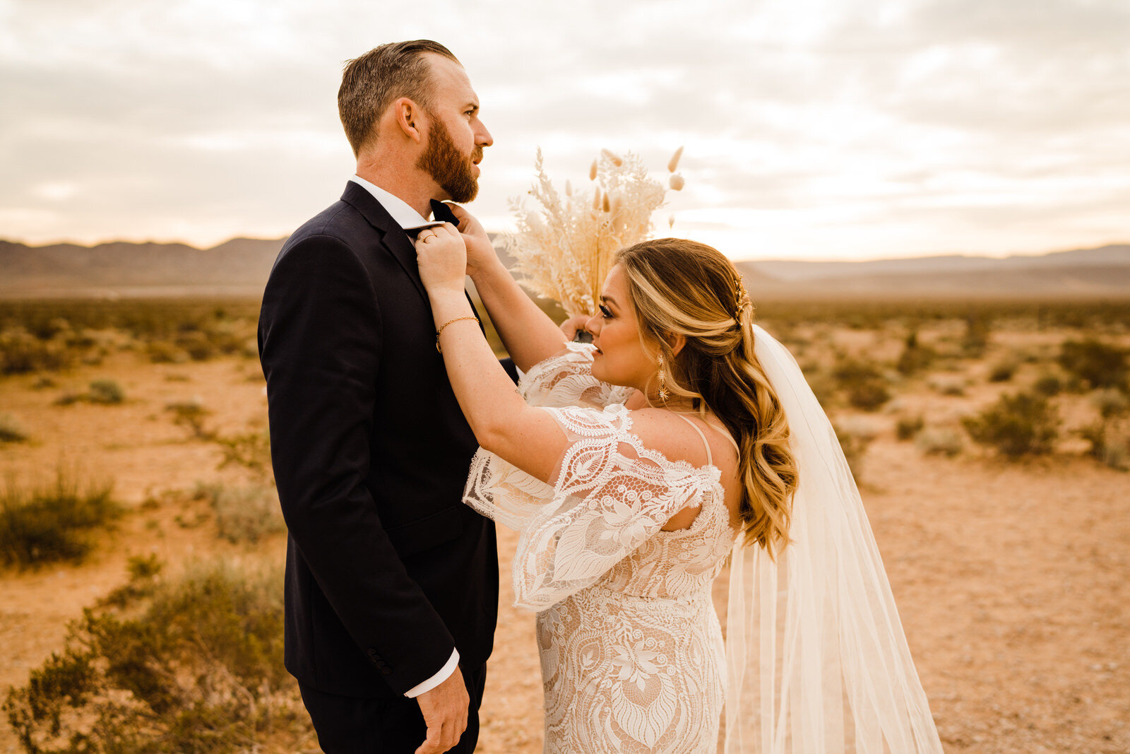 Bride fixes groom's bow tie in Las Vegas desert at sunrise first look