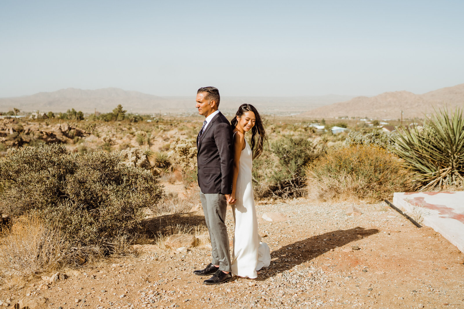 Bride and groom stand back to back at Joshua Tree airbnb for elopement first look | fun, nontraditional wedding photos by California Elopement Photographer Planner Kept Record | www.keptrecord.com