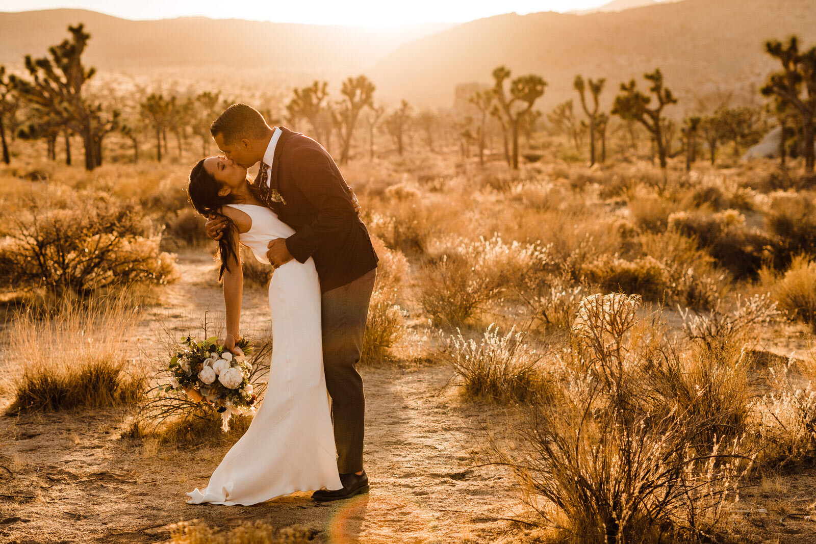 Joshua-Tree-Wedding-Photographer-Groom-Dips-Bride-At-Sunset-Surrounded-by-Cacti-In-Joshua-Tree-National-Park.jpg