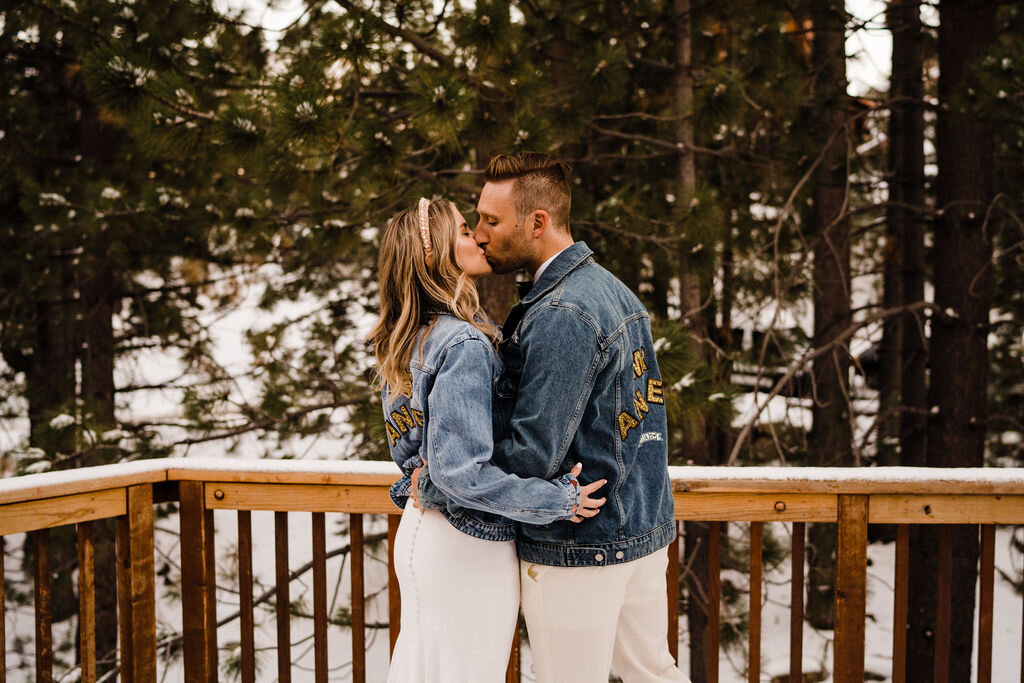 Snowy-Lake-Tahoe-Cabin-Elopement-Bride-and-Groom-with-Matching-Custom-Jean-Jackets-Kiss-In-Snow.jpg